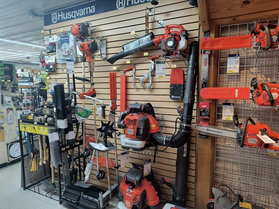Hardware store display of Husqvarna power tools, saws, and trimmers on a pegboard wall