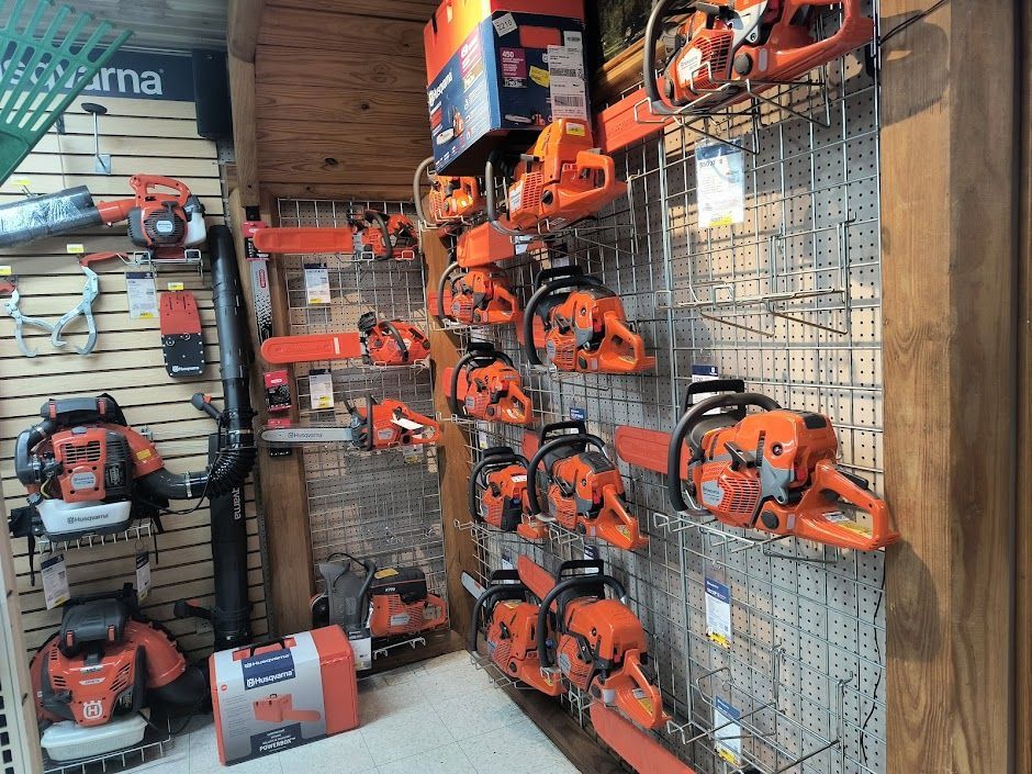 Wall of orange chainsaws and outdoor power tools displayed in a store aisle