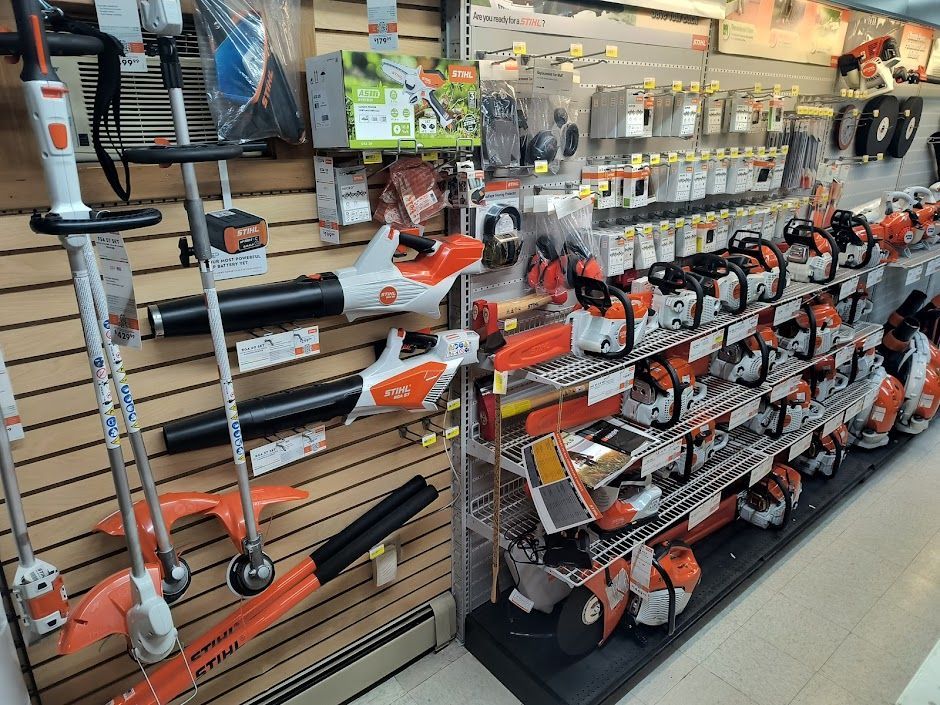 Hardware store display of orange-and-black trimmers and tools on shelves and hooks
