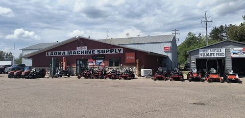 Farm and home supply store with ATVs and tractors parked outside on a cloudy day