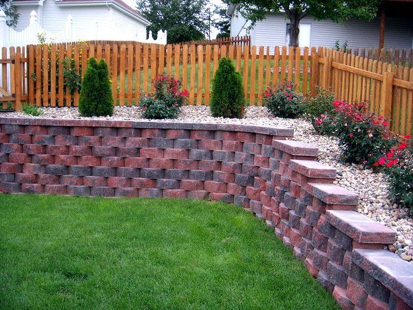 a backyard with a retaining wall and a wooden fence