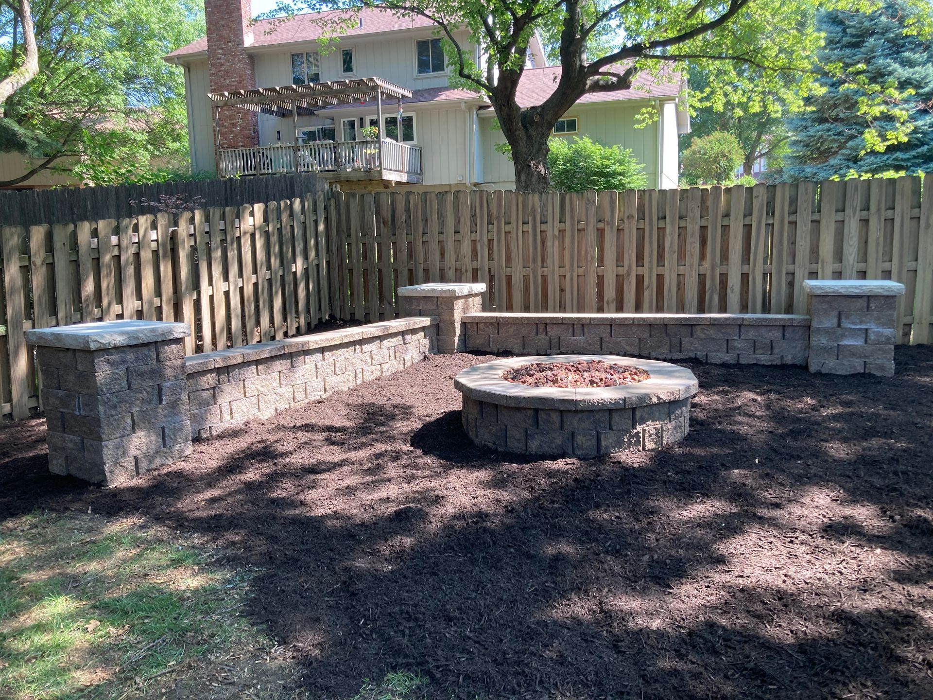 a fire pit is in the middle of a backyard next to a wooden fence