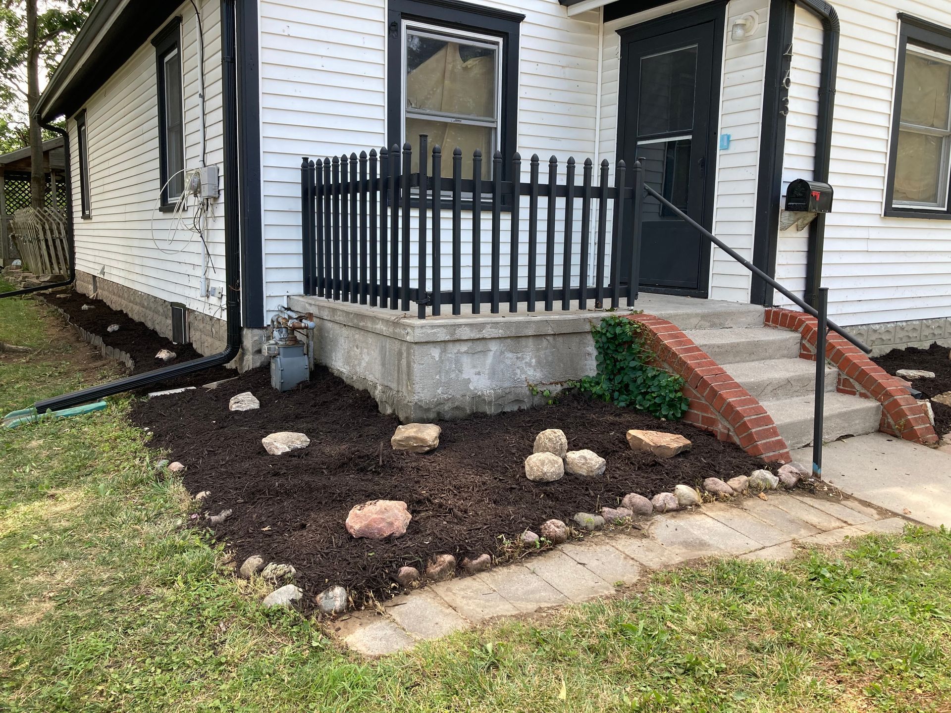 a white house with a black fence and stairs in front of it