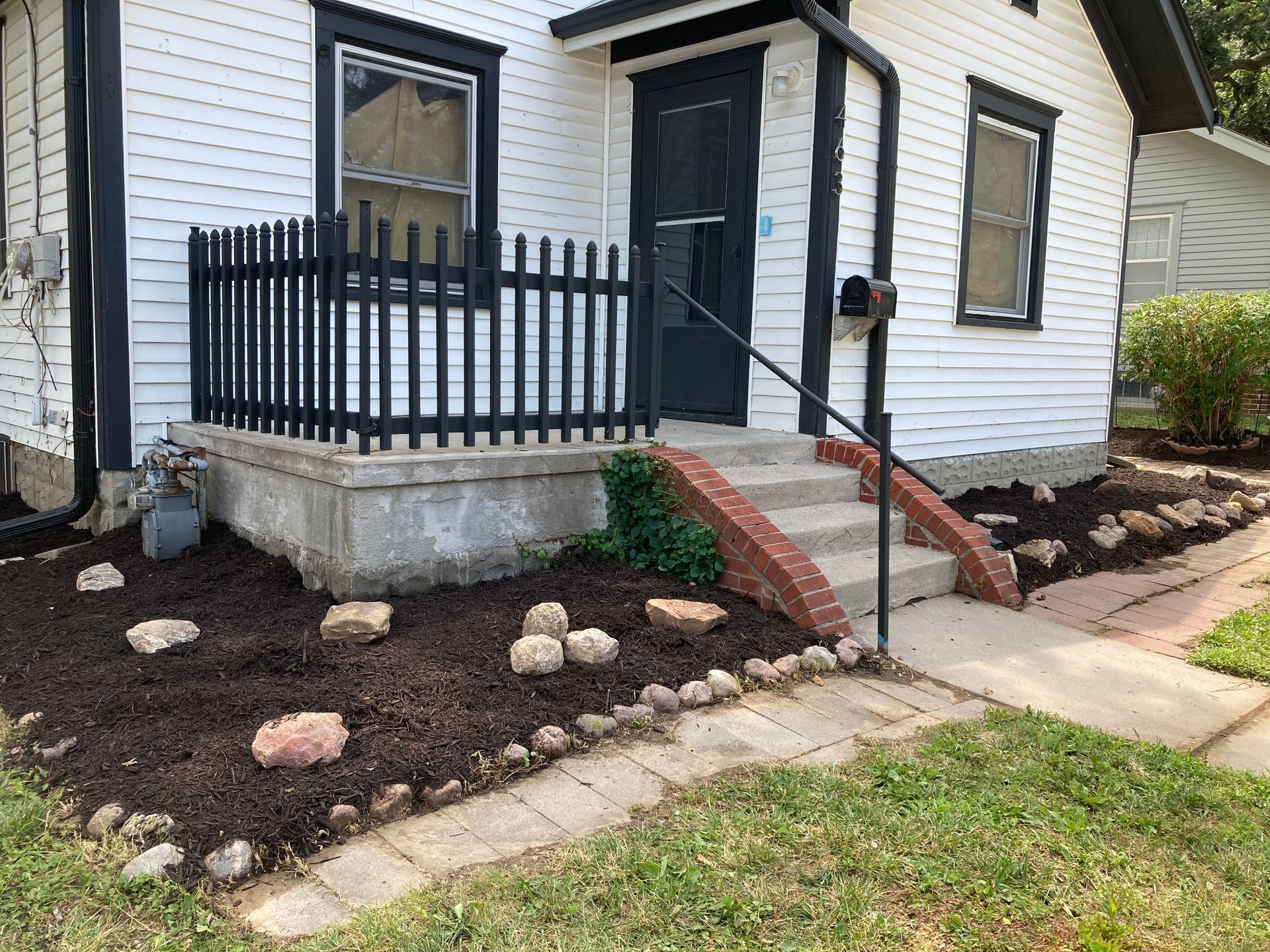 a small white house with a black picket fence and stairs