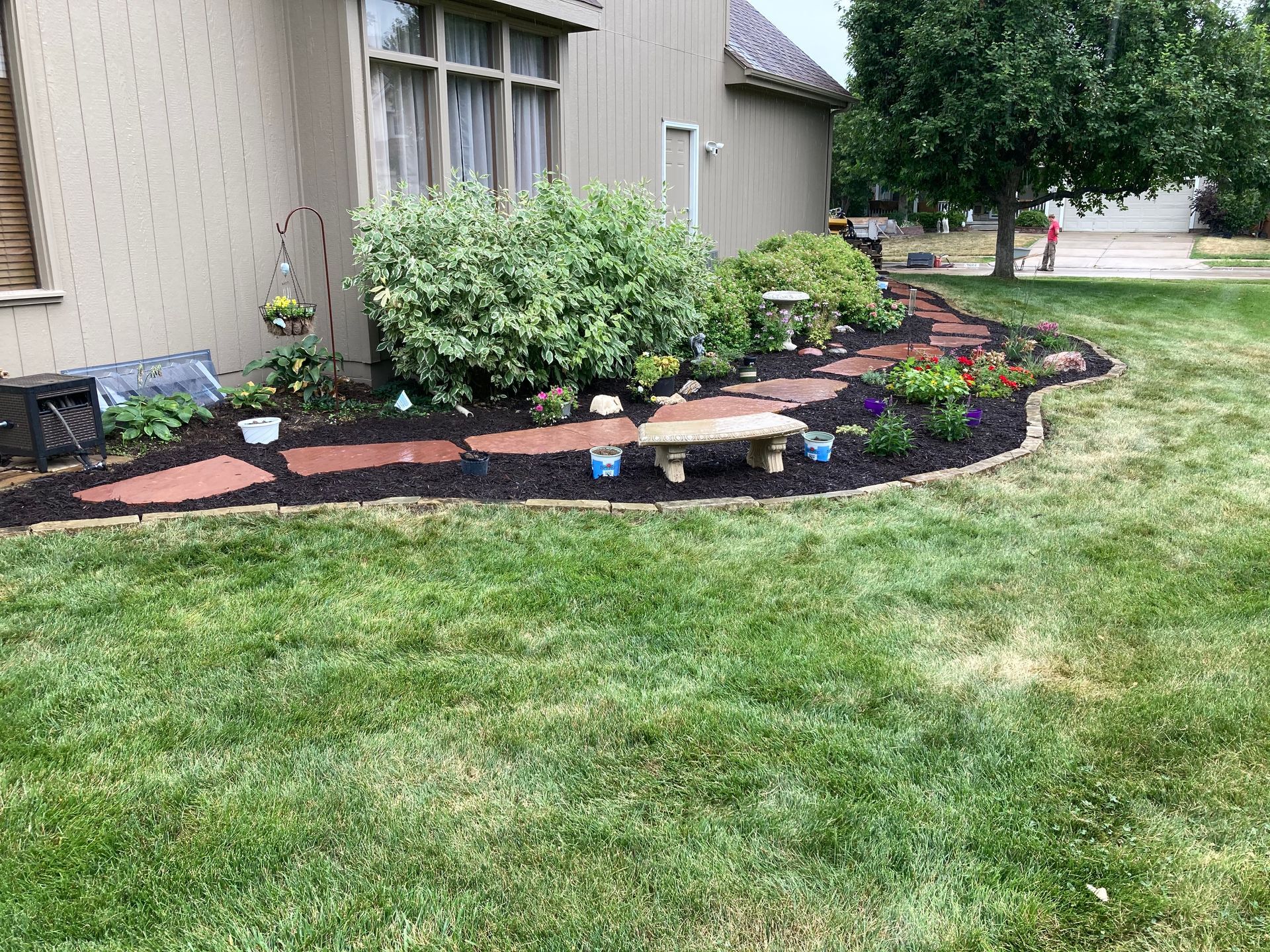 there is a bench in the middle of the garden in front of the house