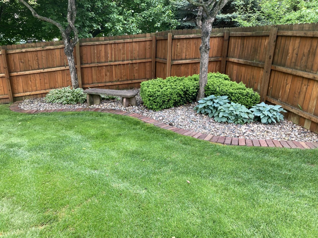 a wooden fence surrounds a lush green lawn in a backyard