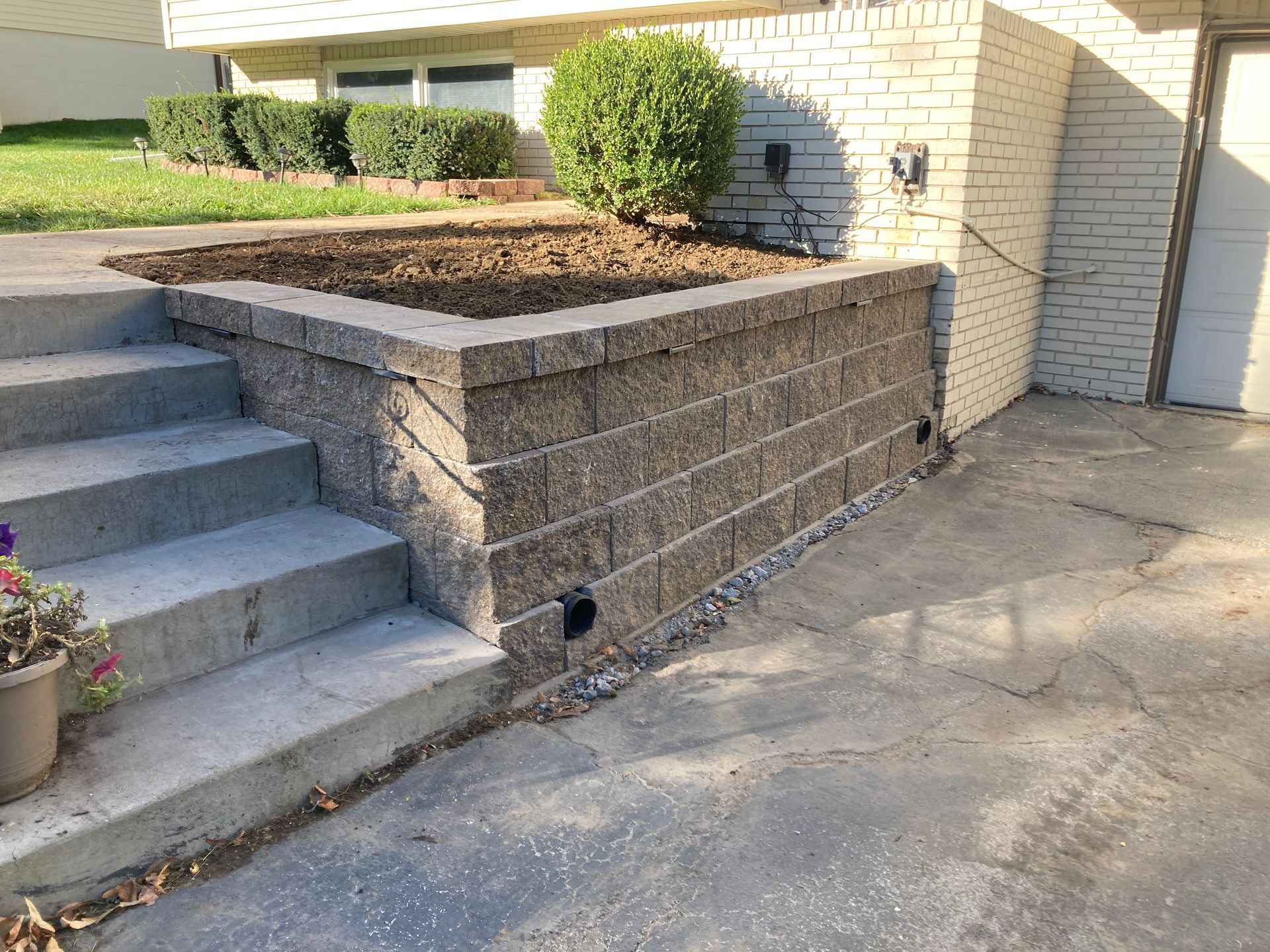 a brick wall with stairs leading up to it in front of a house