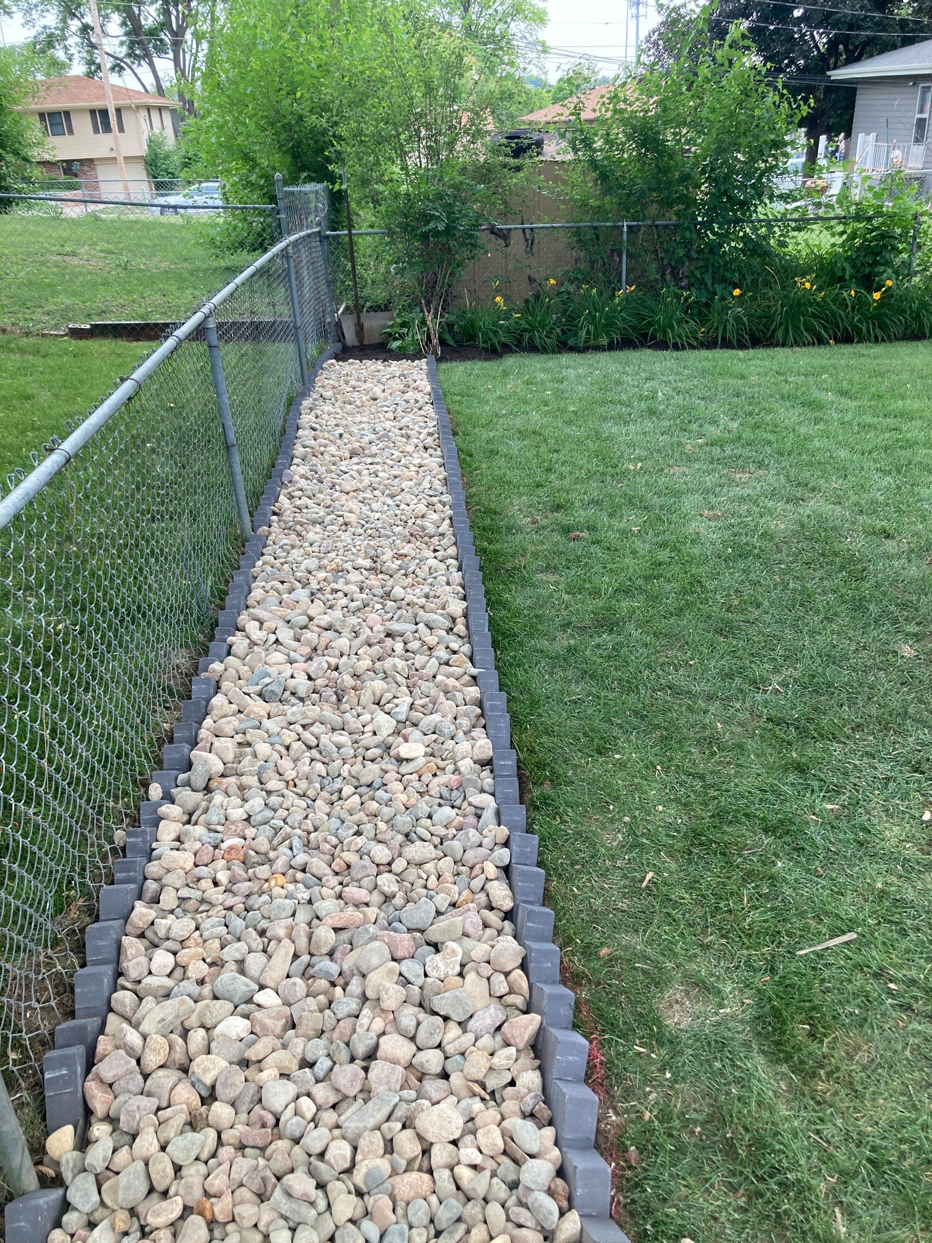 a stone walkway leading to a fence in a backyard