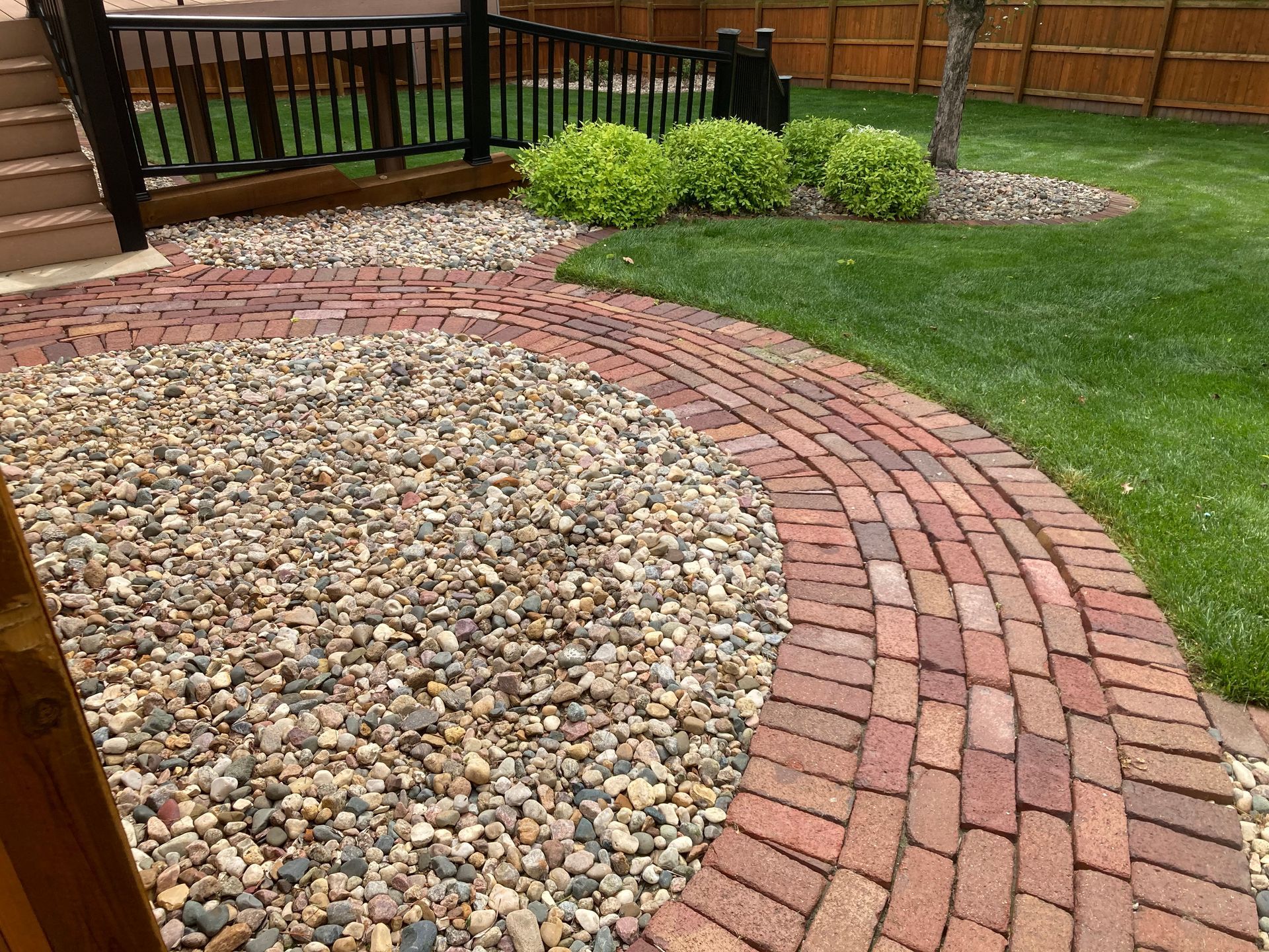 a brick walkway surrounded by gravel and grass in a backyard