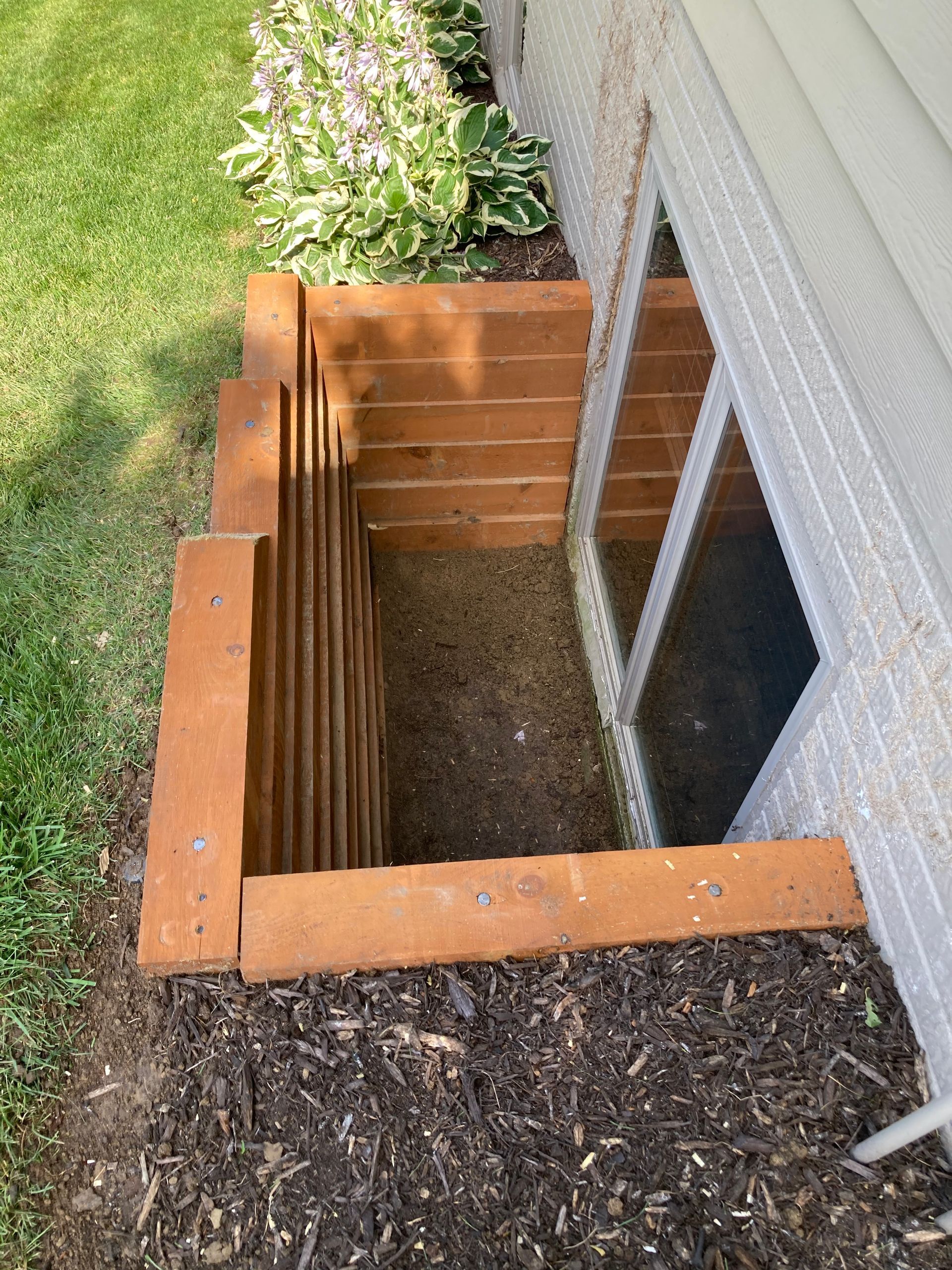 a wooden staircase is built into the side of a house next to a window