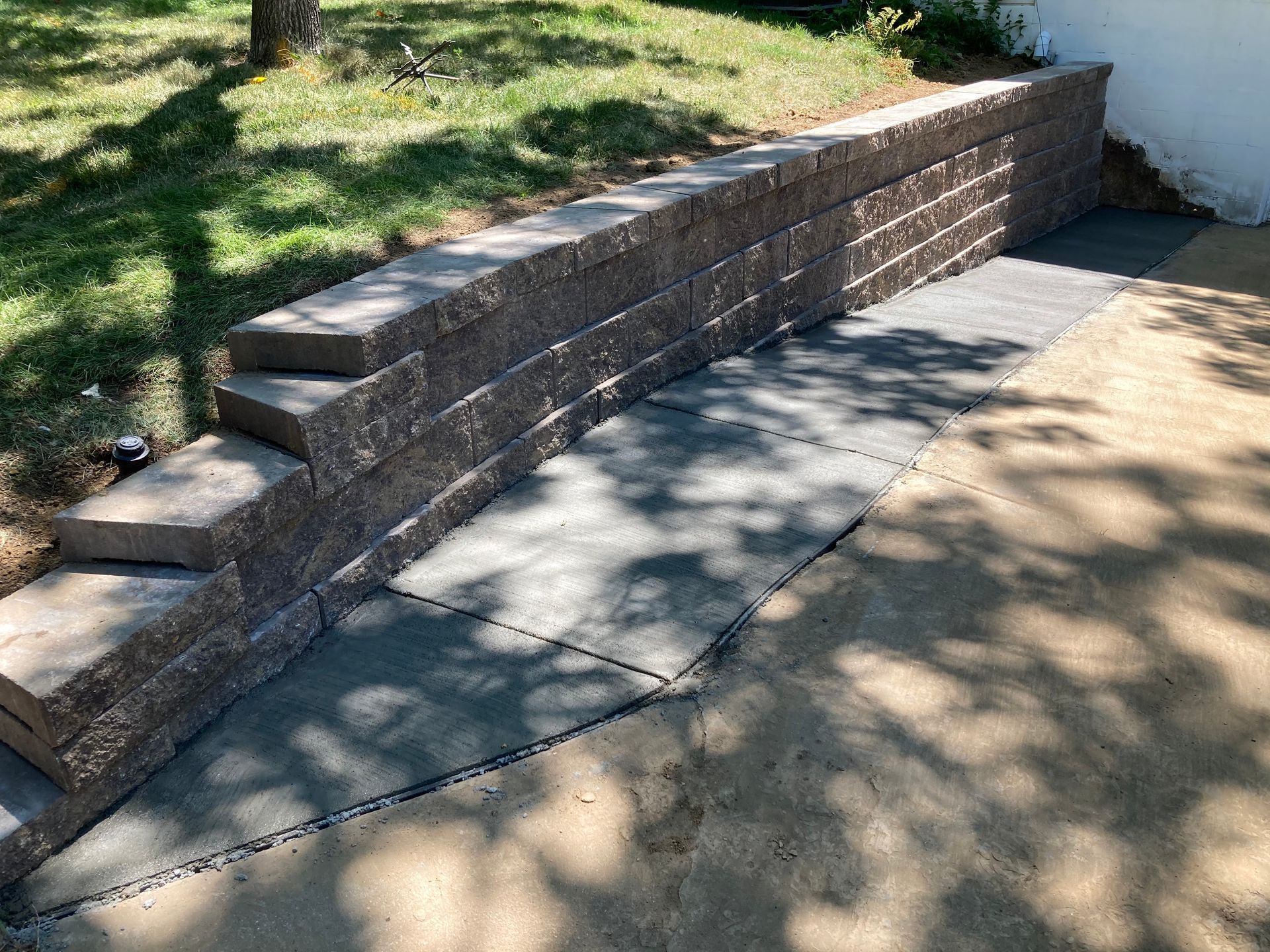a stone wall with steps leading up to it and a concrete walkway