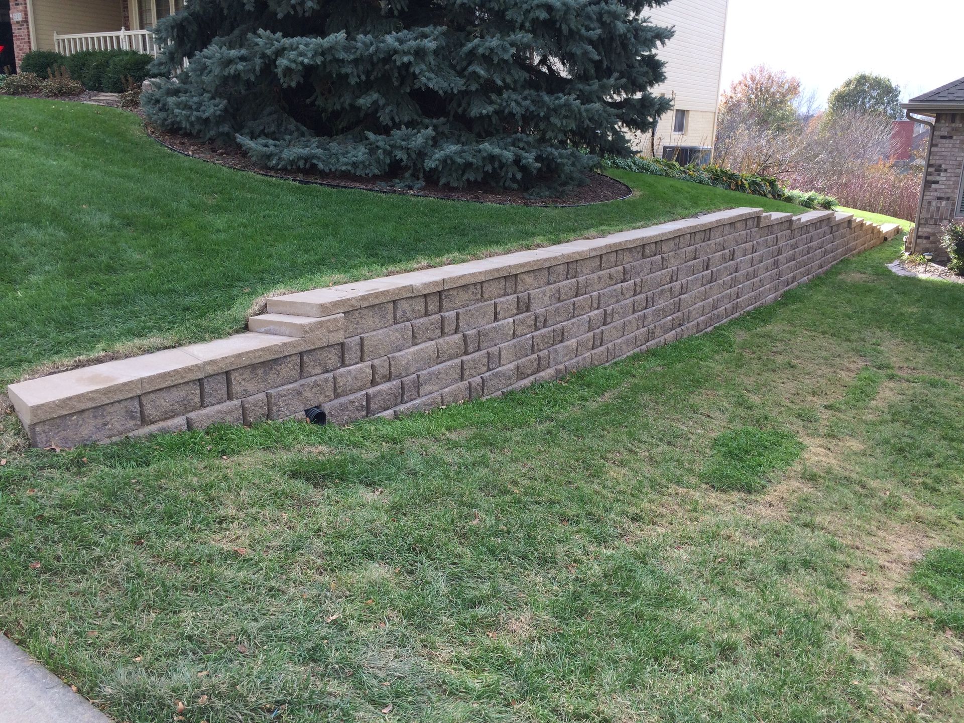 a brick wall is sitting in the middle of a lush green lawn