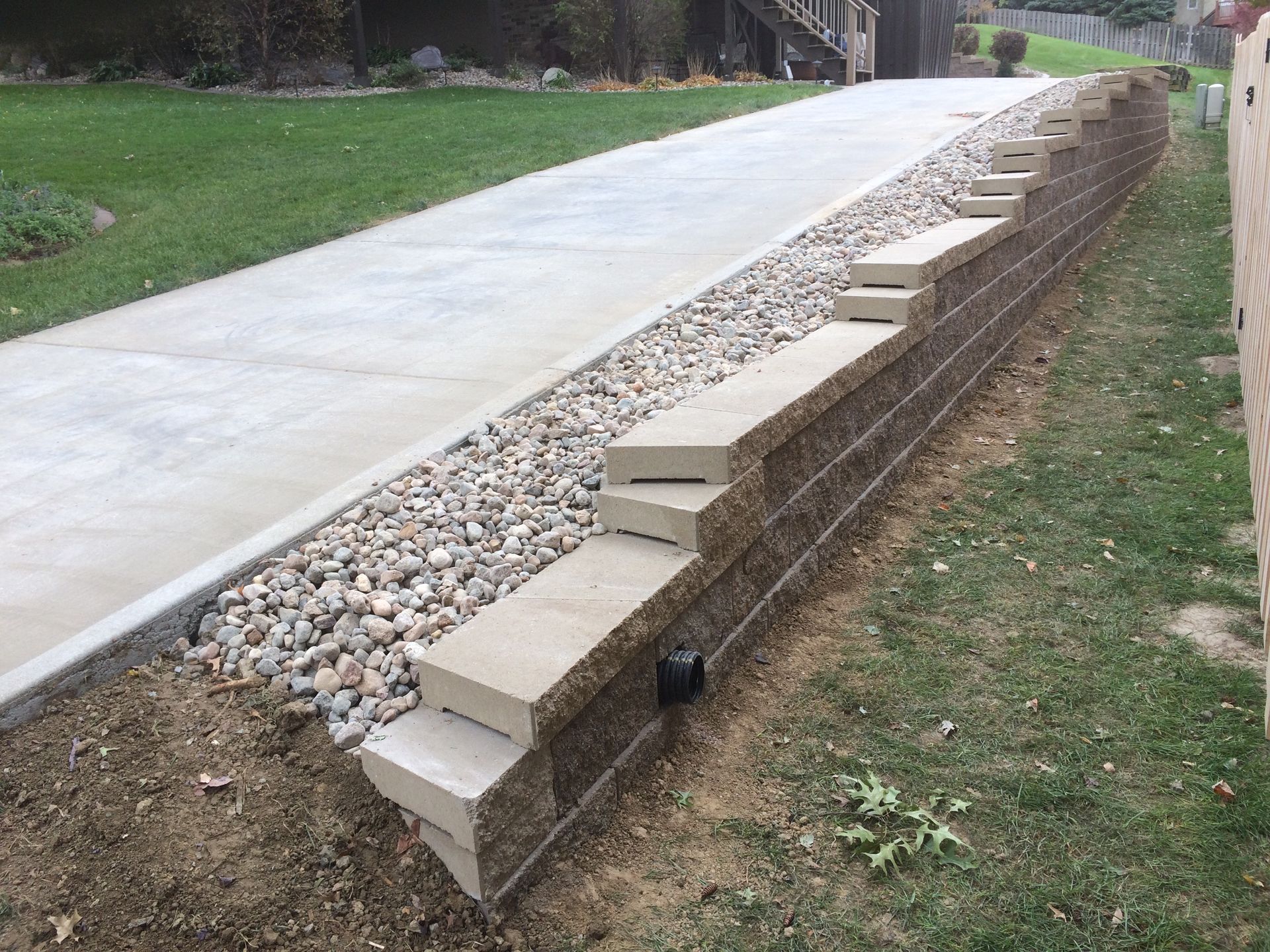 a concrete driveway with a stone wall along the side of it