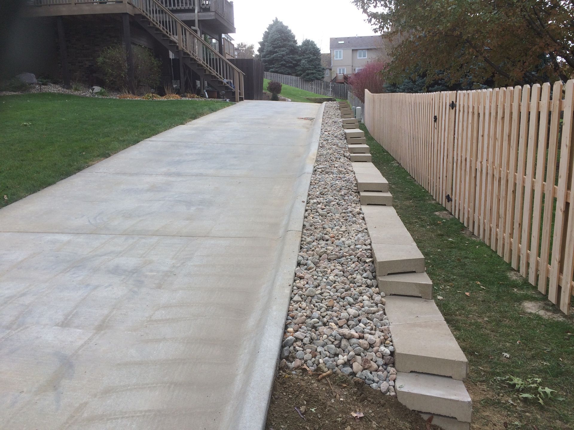 a wooden fence along the side of a concrete driveway