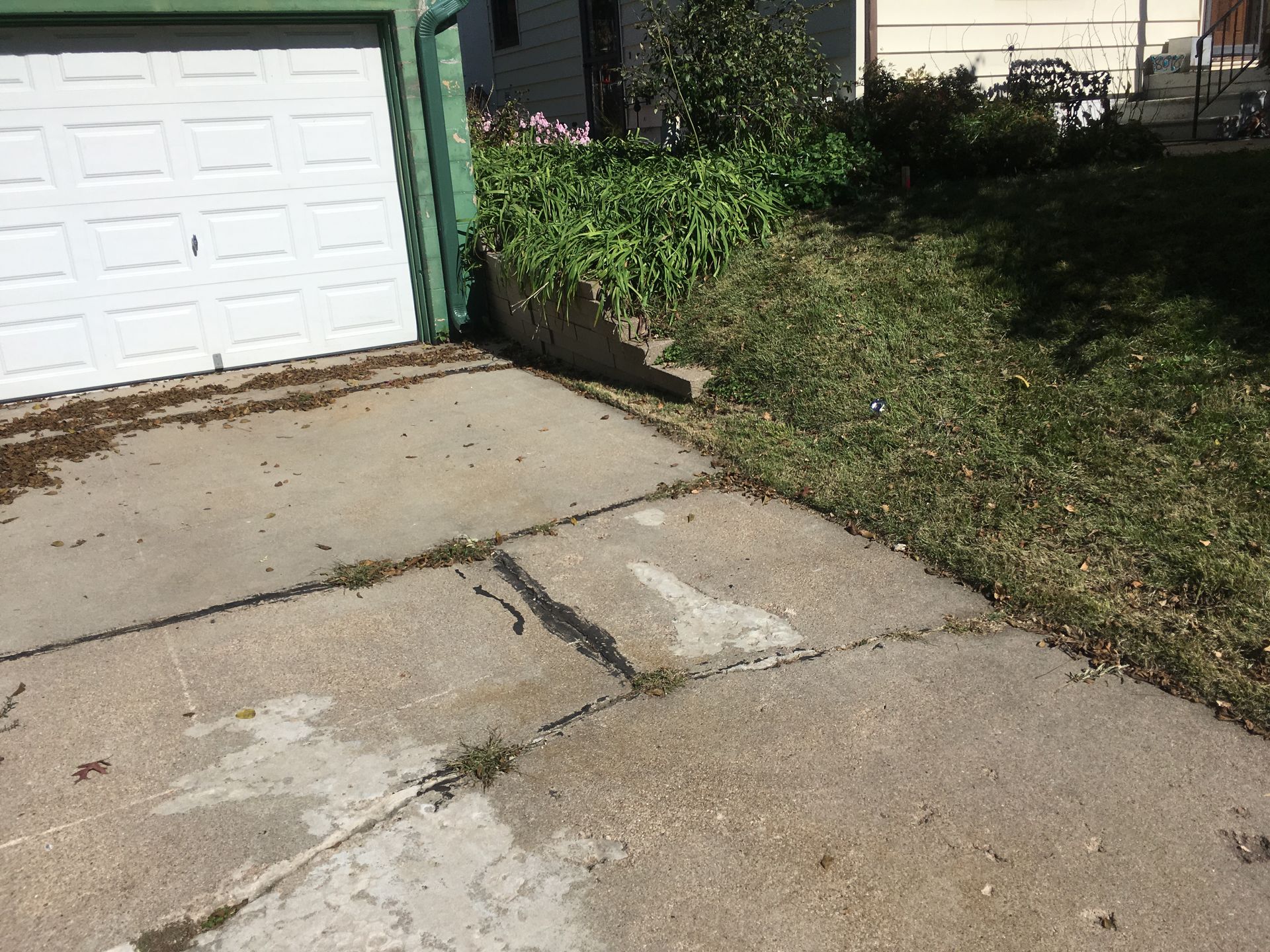 a concrete driveway next to a garage door and a house