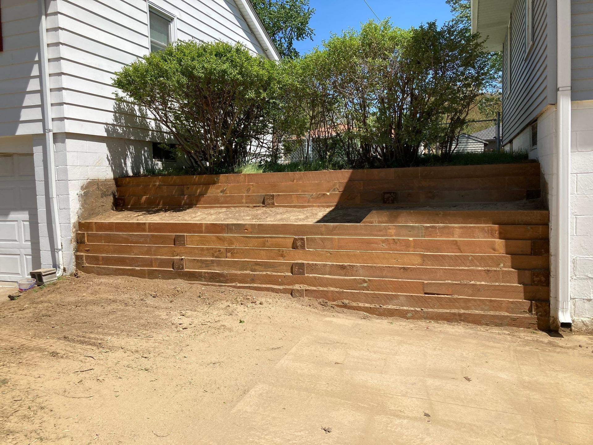 a wooden retaining wall is being built in front of a house