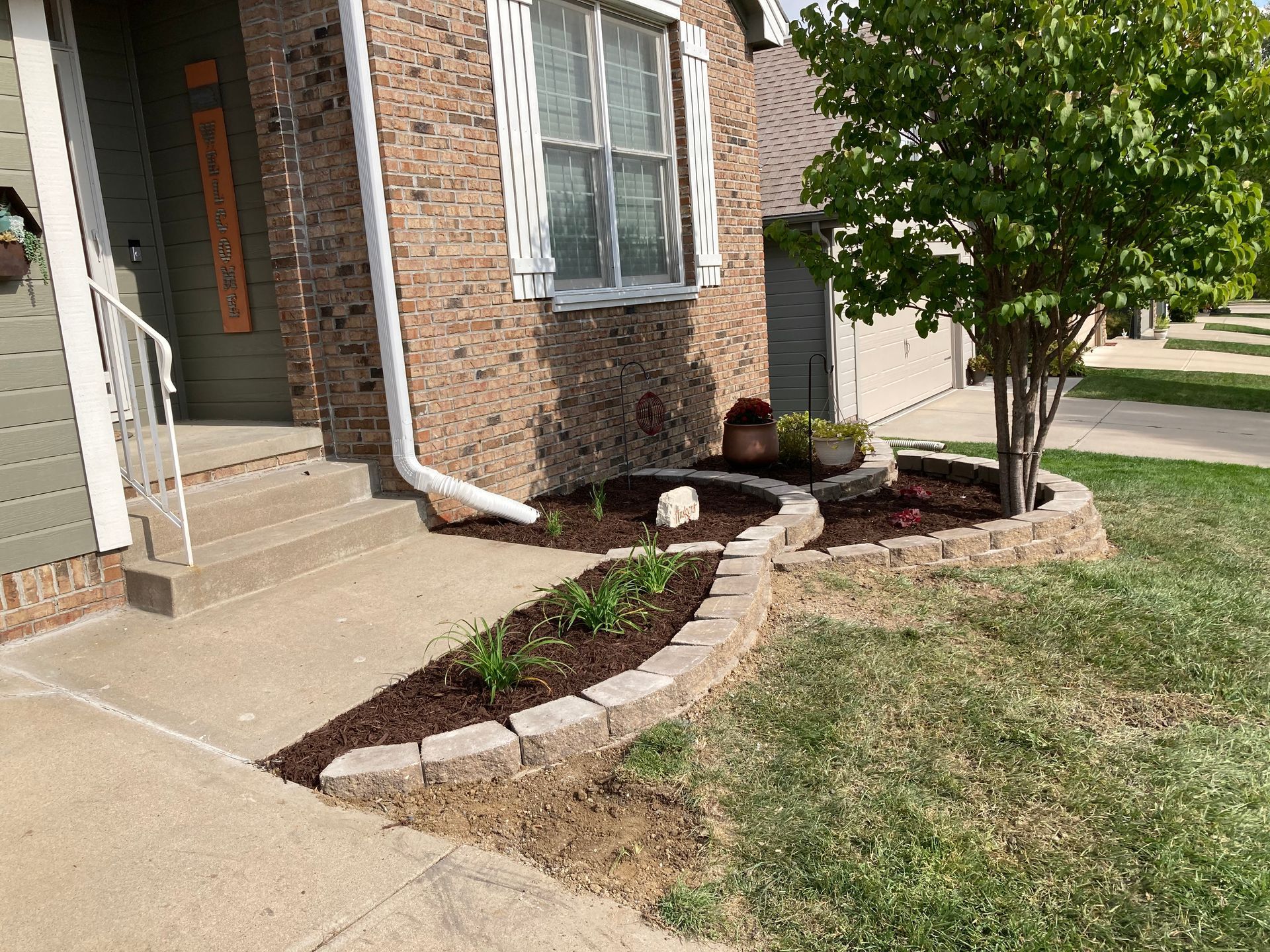 a brick house with a sidewalk and a tree in front of it