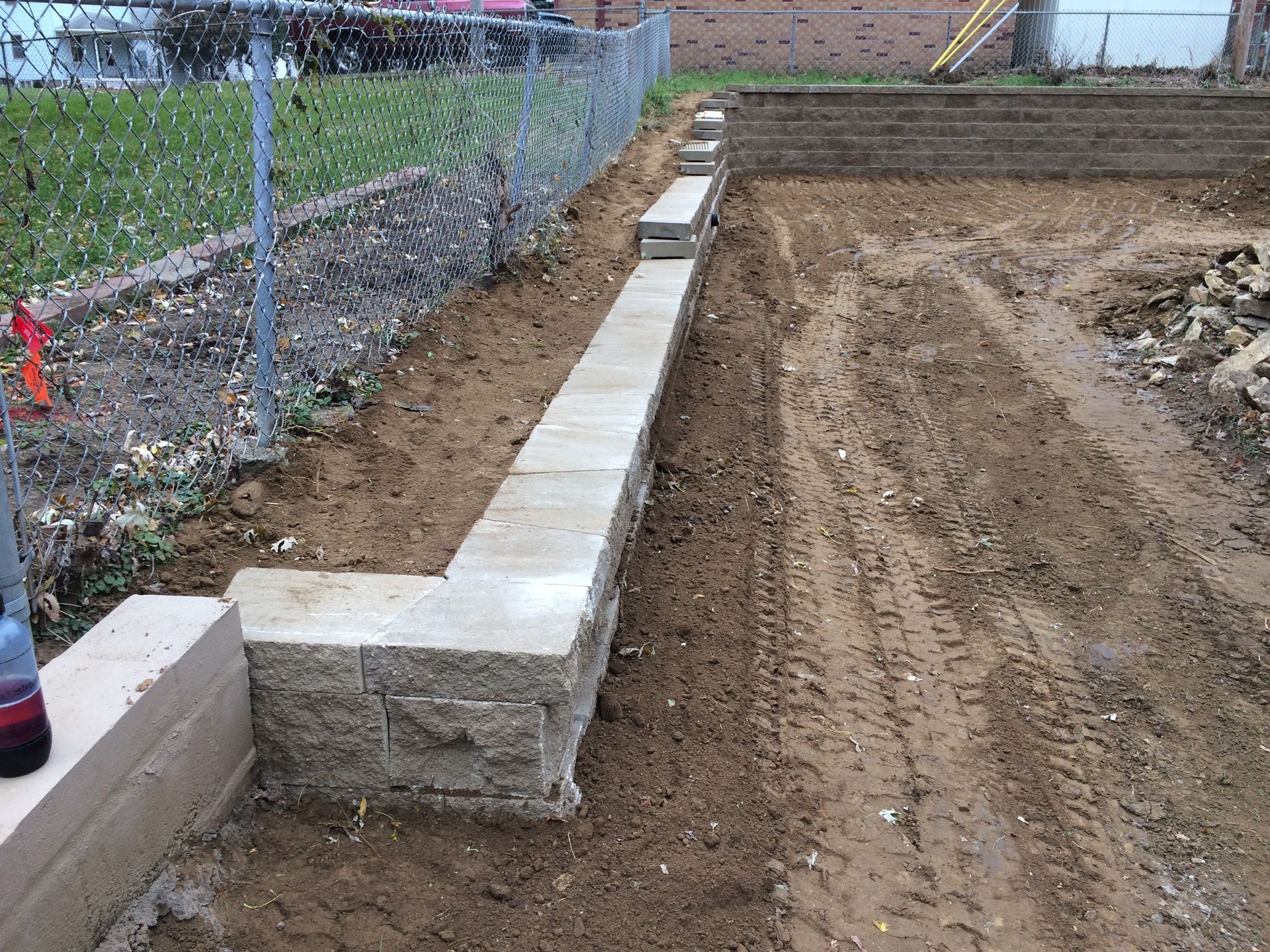 a concrete wall is being built next to a chain link fence