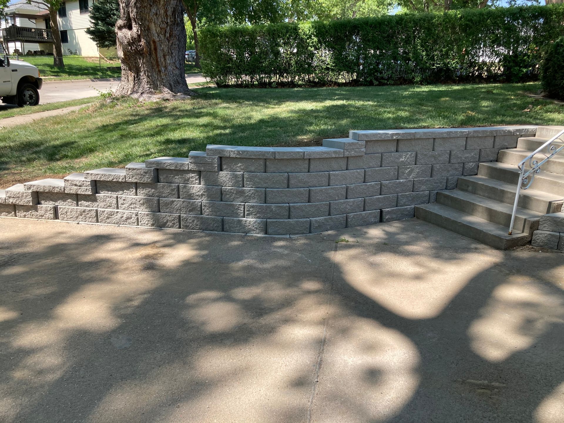 a brick wall with stairs and a tree in the background