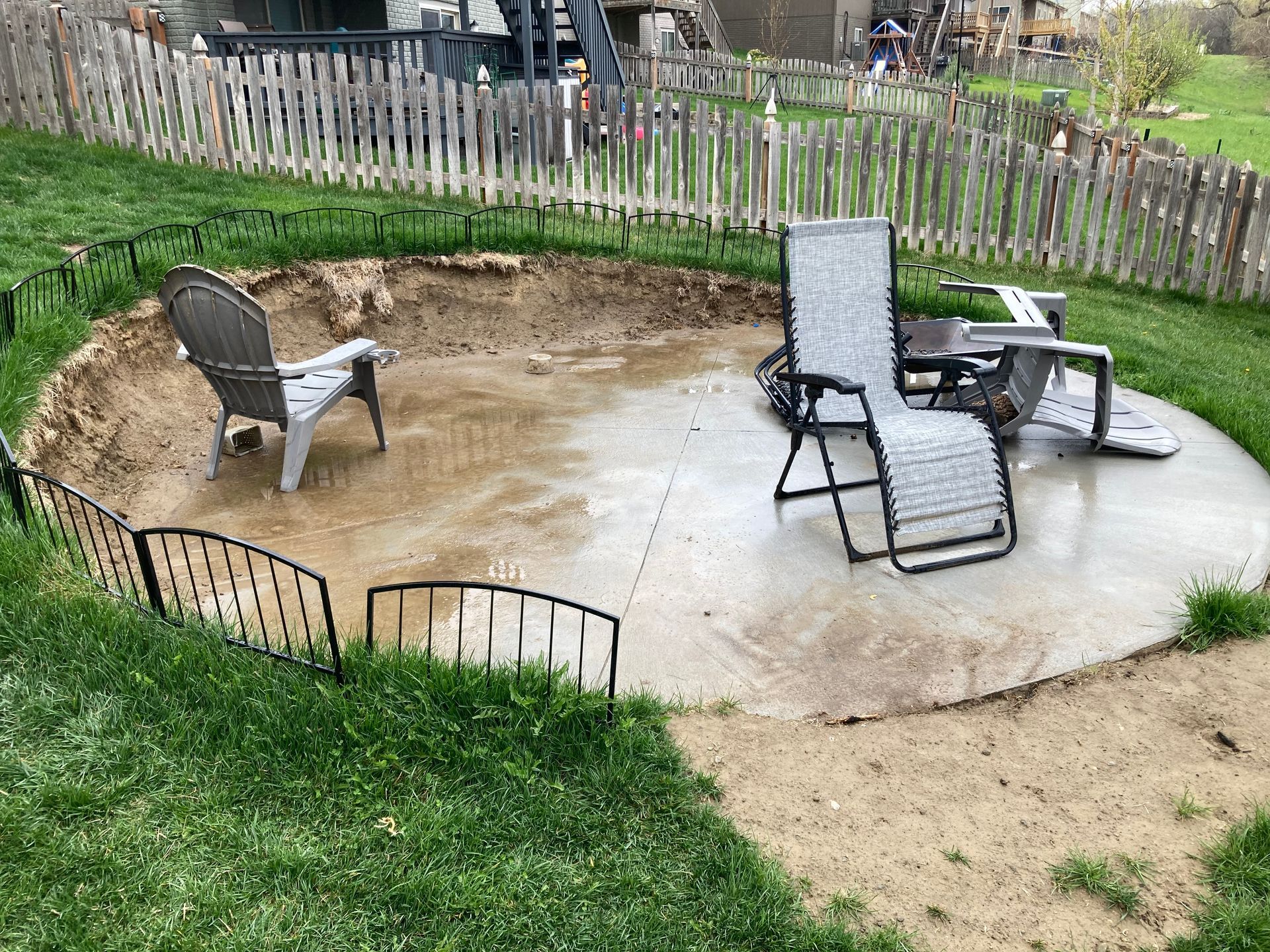 a fire pit is being built in a backyard with chairs and a fence