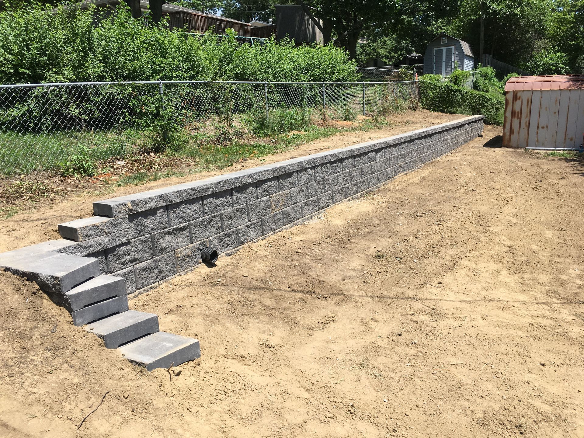 a stone wall with stairs leading up to it in a backyard