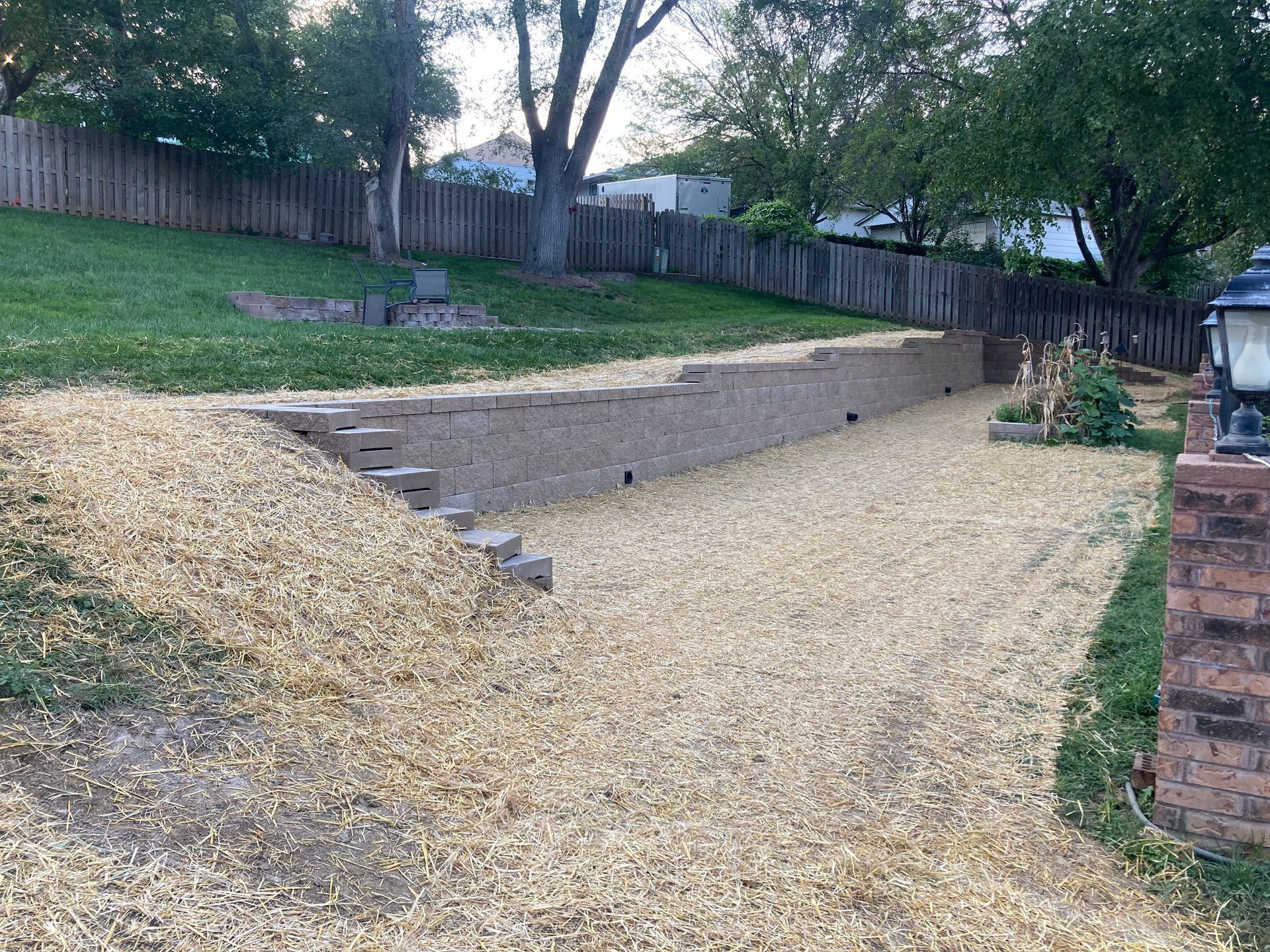a gravel driveway leading to a house with a brick wall and stairs