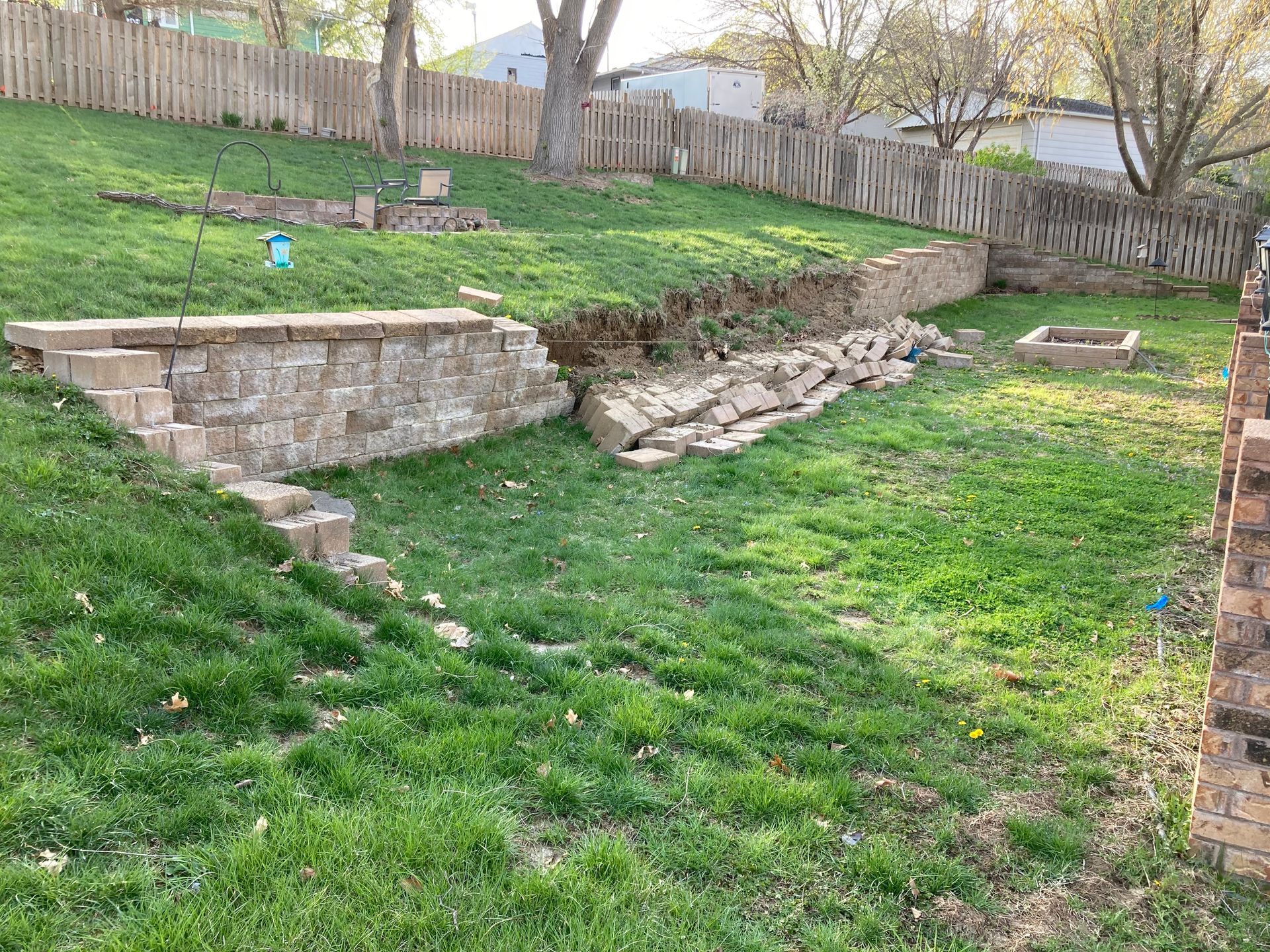 a lush green yard with a stone wall and a wooden fence