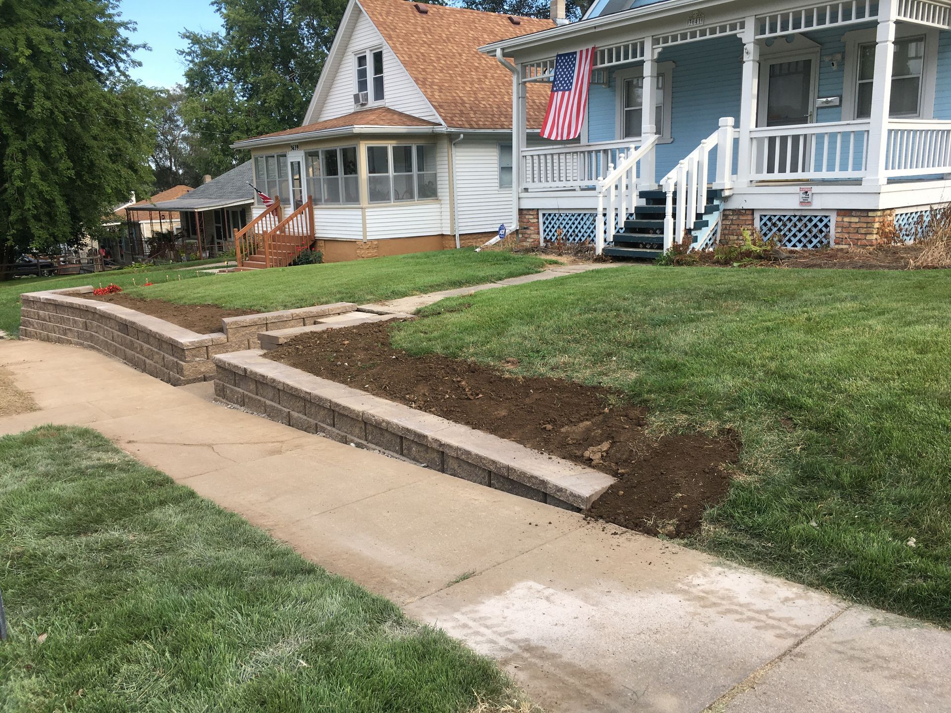 a house with a flag on the porch and a sidewalk in front of it
