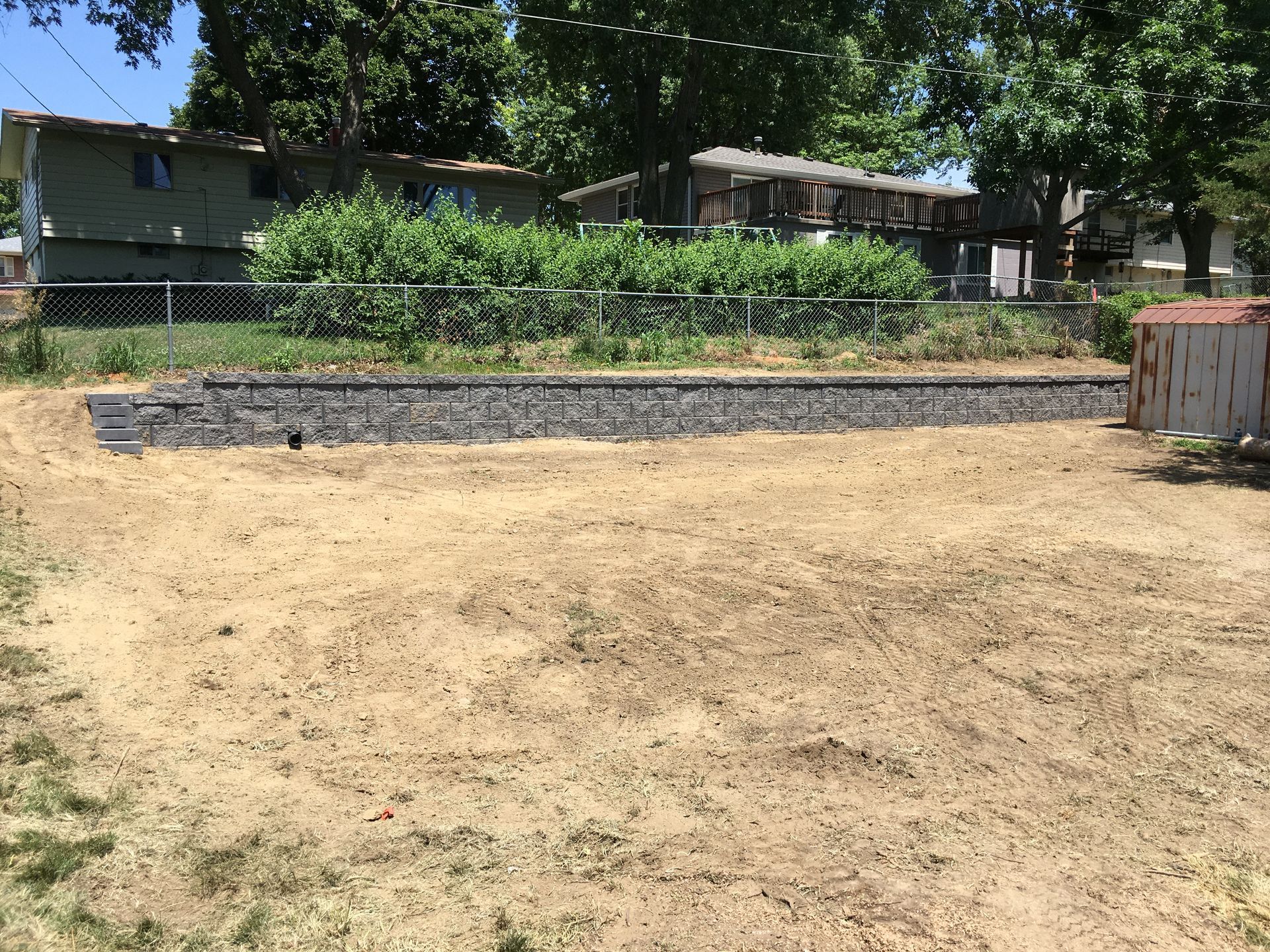 a large dirt field with a fence and a house in the background