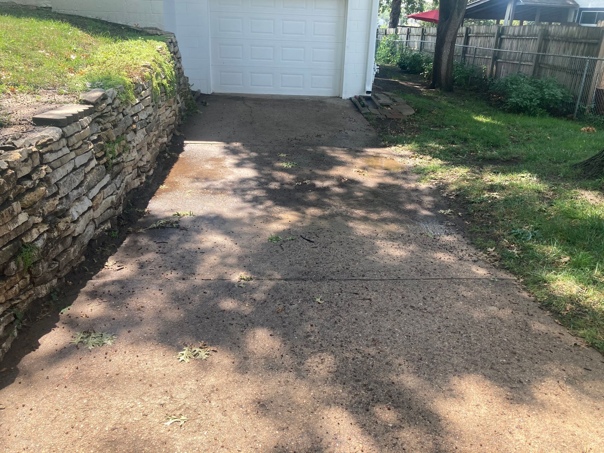 a concrete driveway leading to a garage with a stone wall