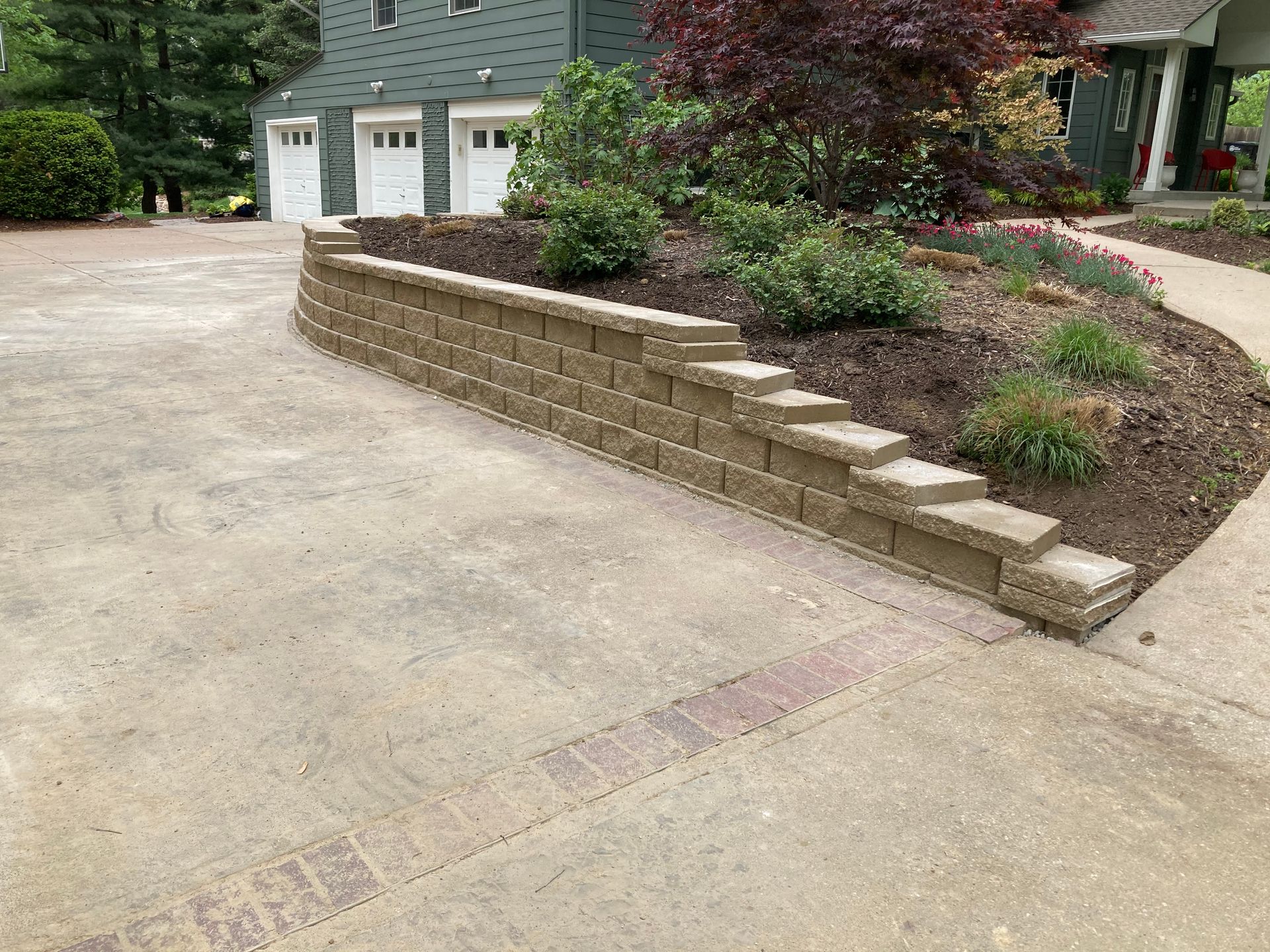 a driveway with a brick wall and steps leading to a house