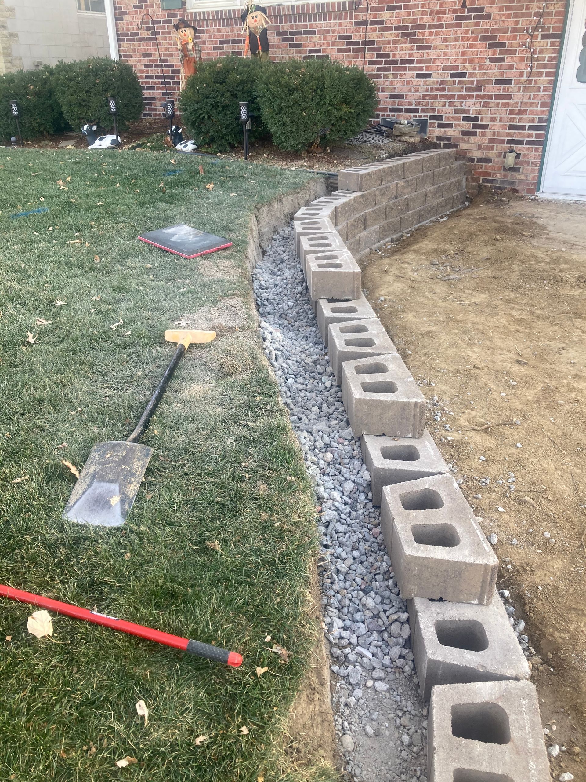a shovel is sitting on the grass next to a row of concrete blocks