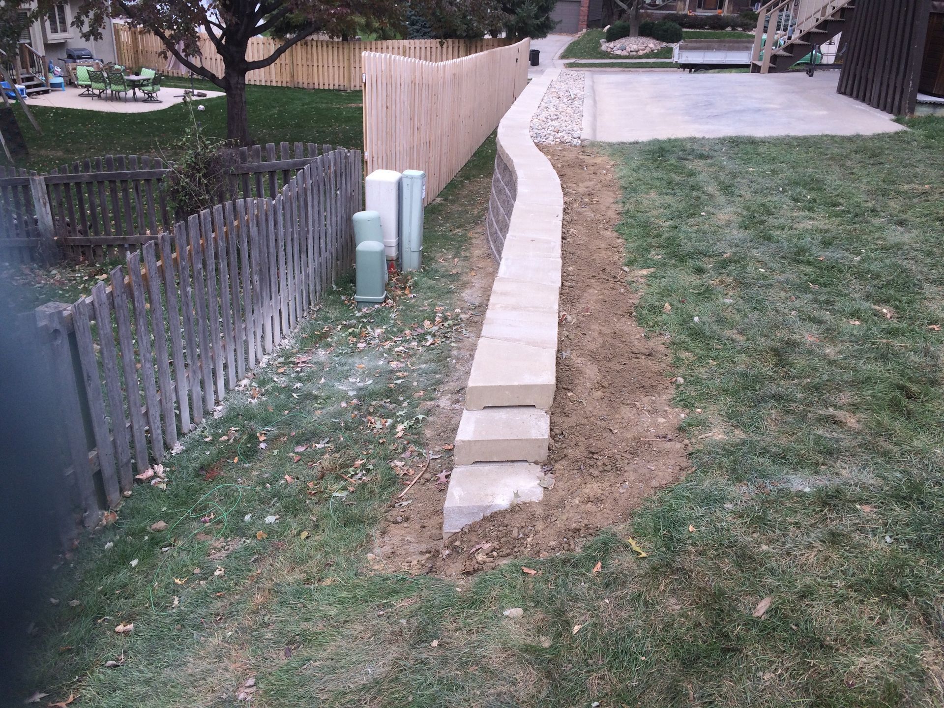 a concrete walkway is being built in a backyard next to a wooden fence