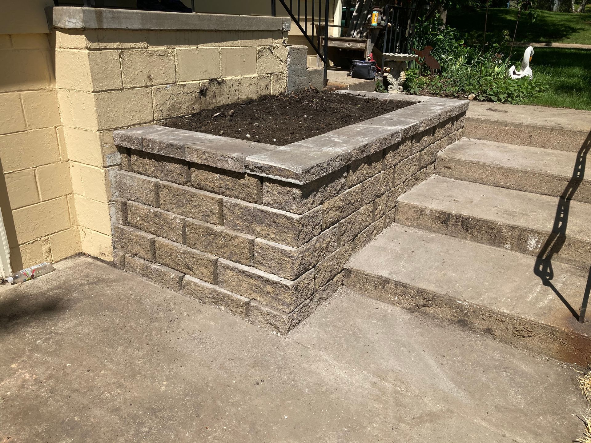a brick wall with a planter on top of it next to a set of stairs