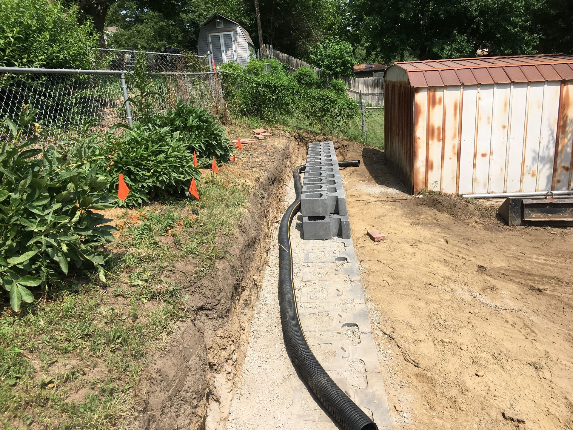 a drain pipe is being installed in a backyard next to a shed