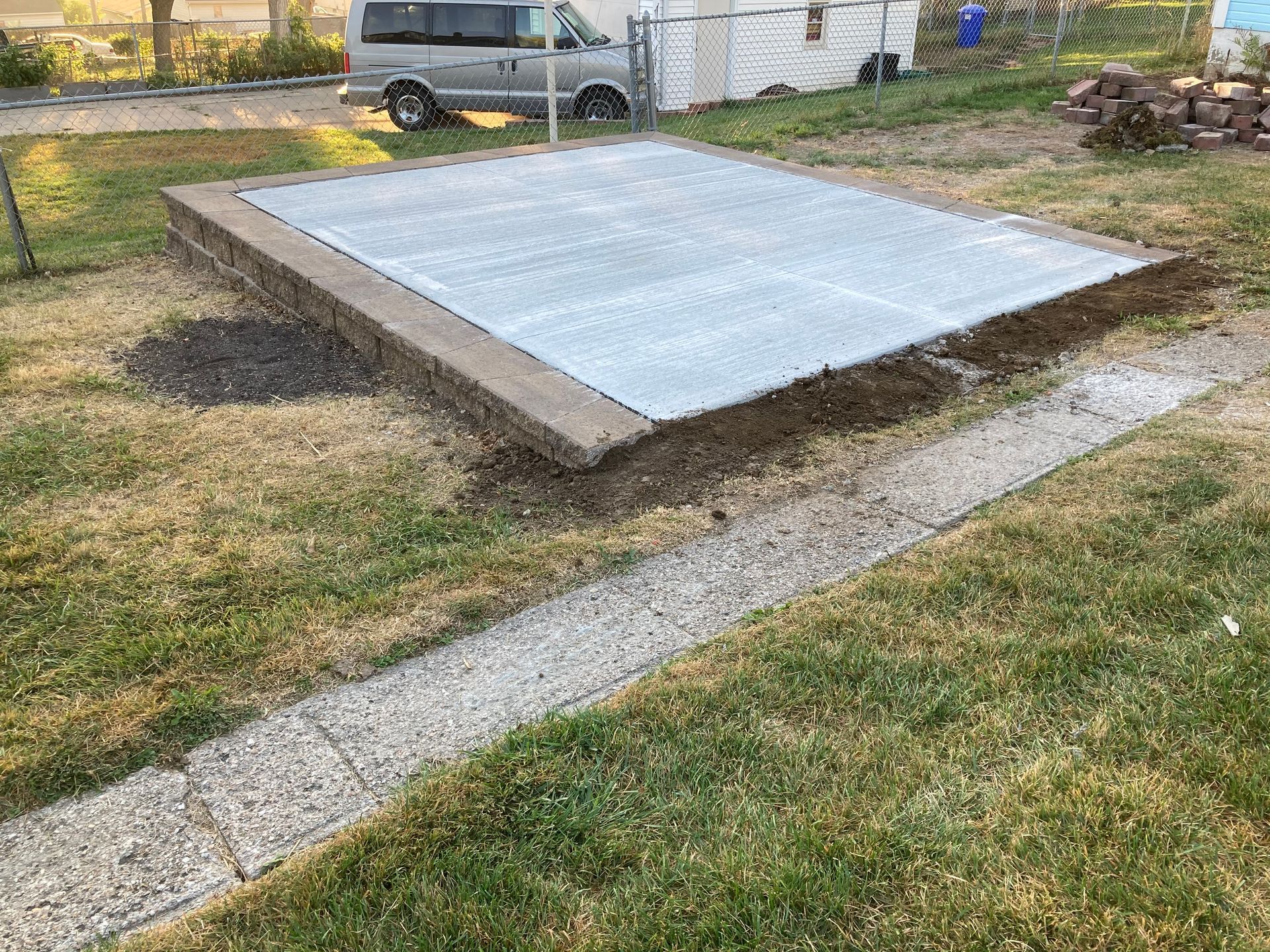 a van is parked in the grass next to a concrete slab