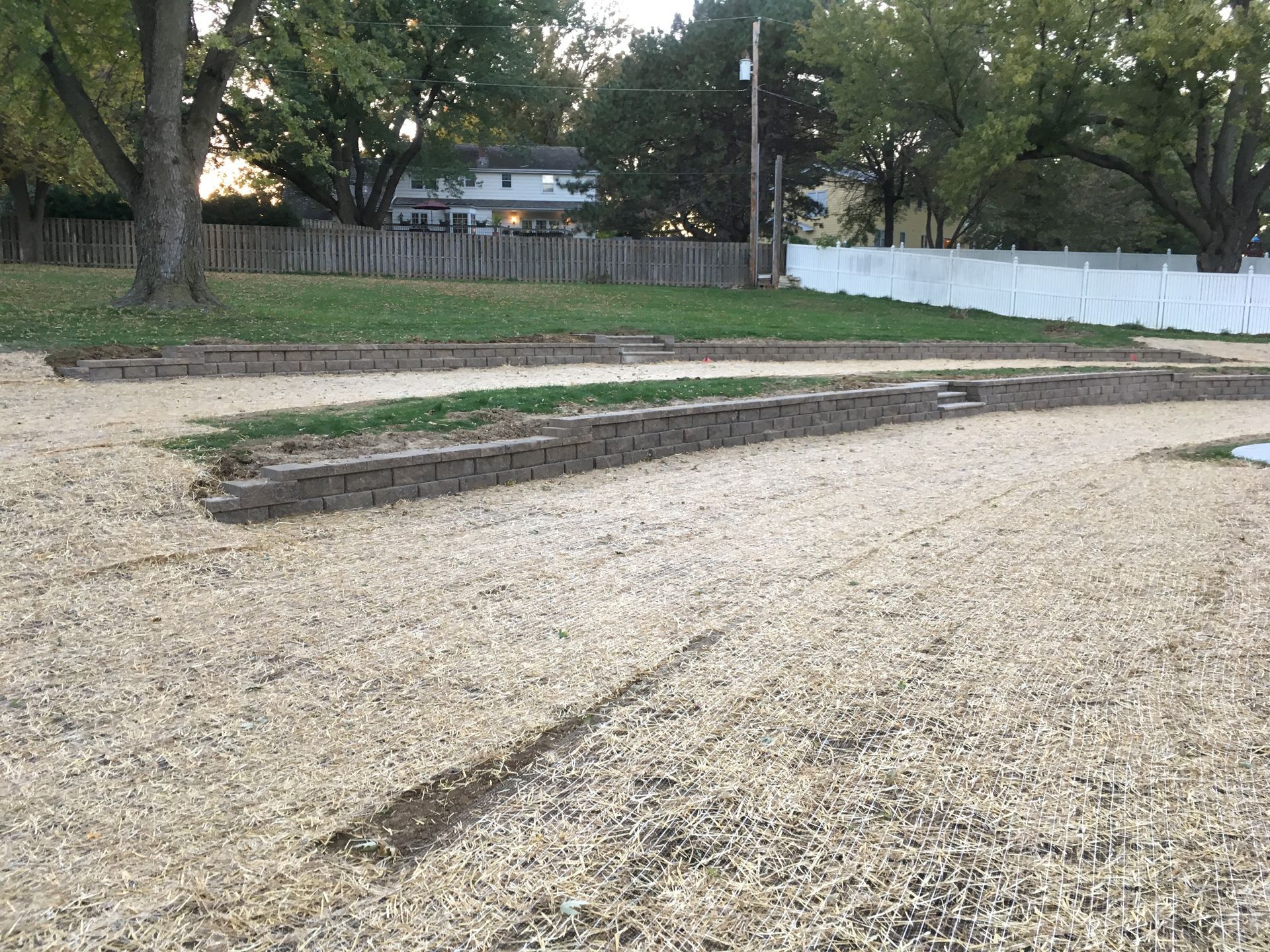 a gravel area with a white fence in the background