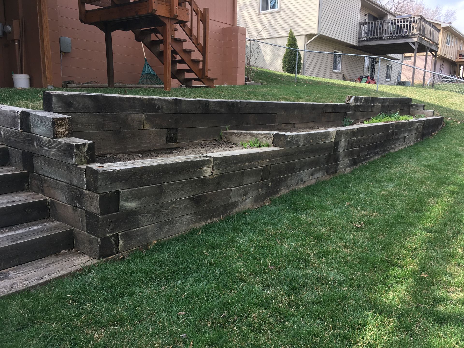 a wooden retaining wall with stairs in front of a house