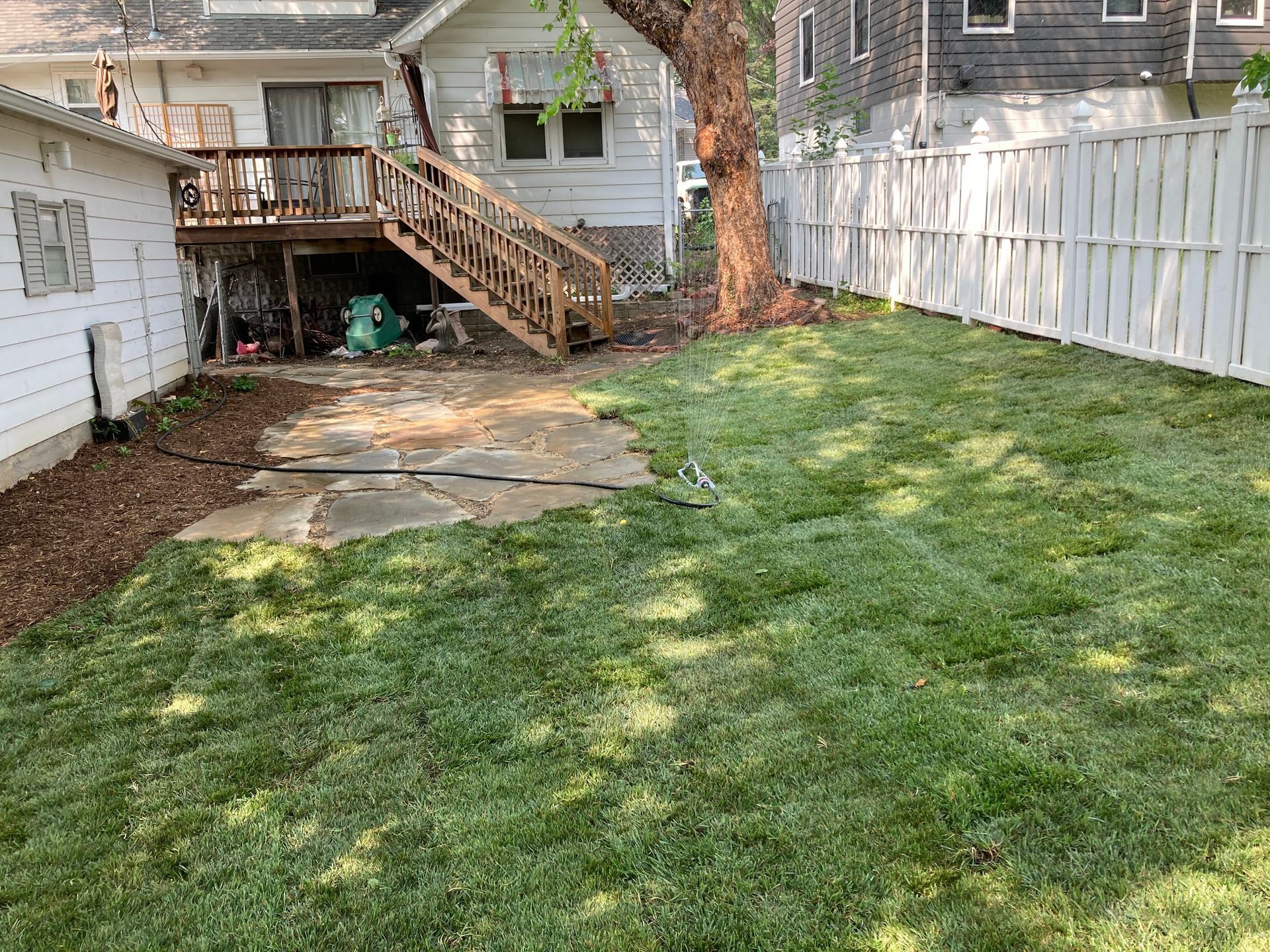 a backyard with a deck and a white fence