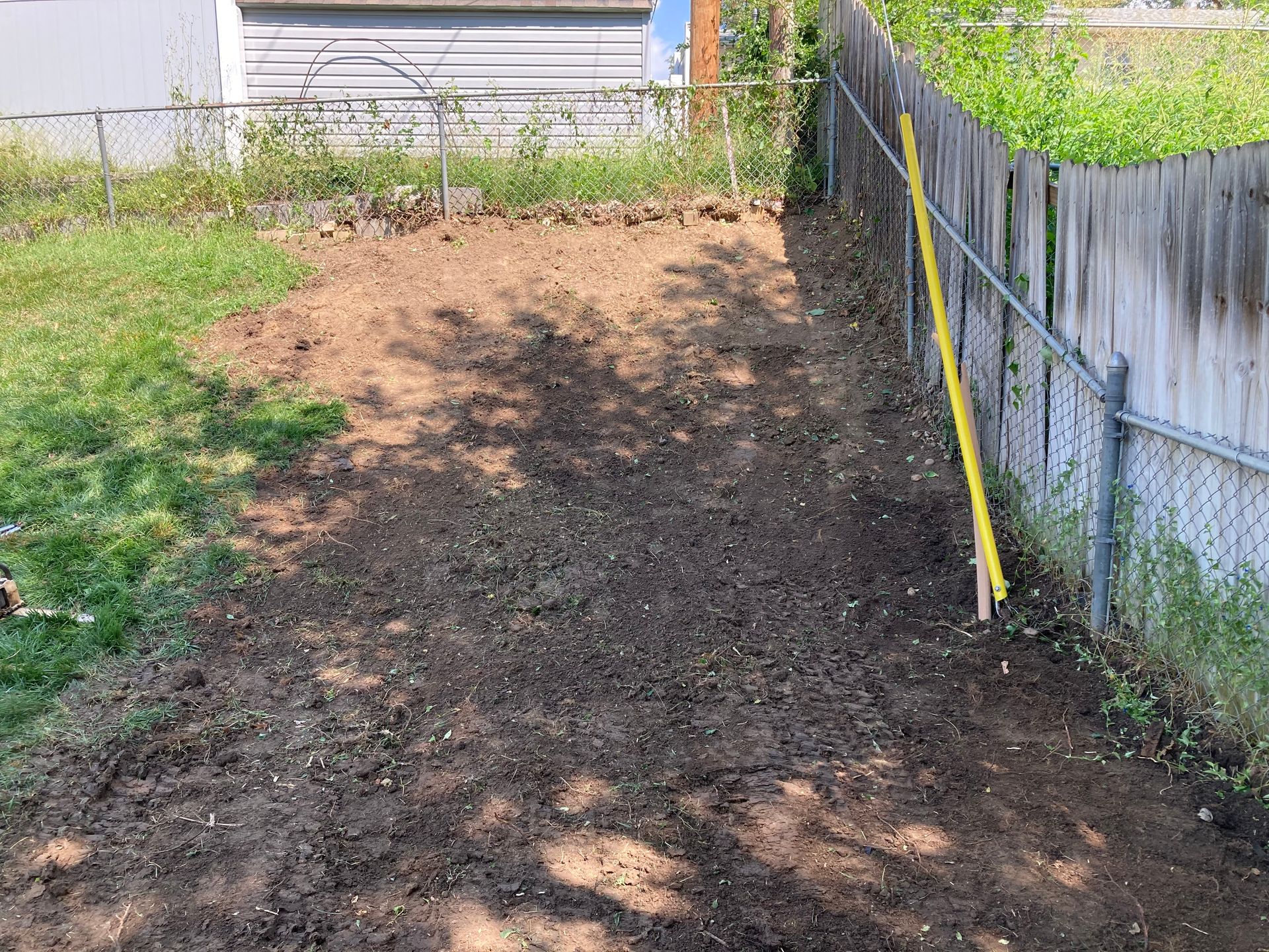 a chain link fence surrounds a dirt area in a backyard
