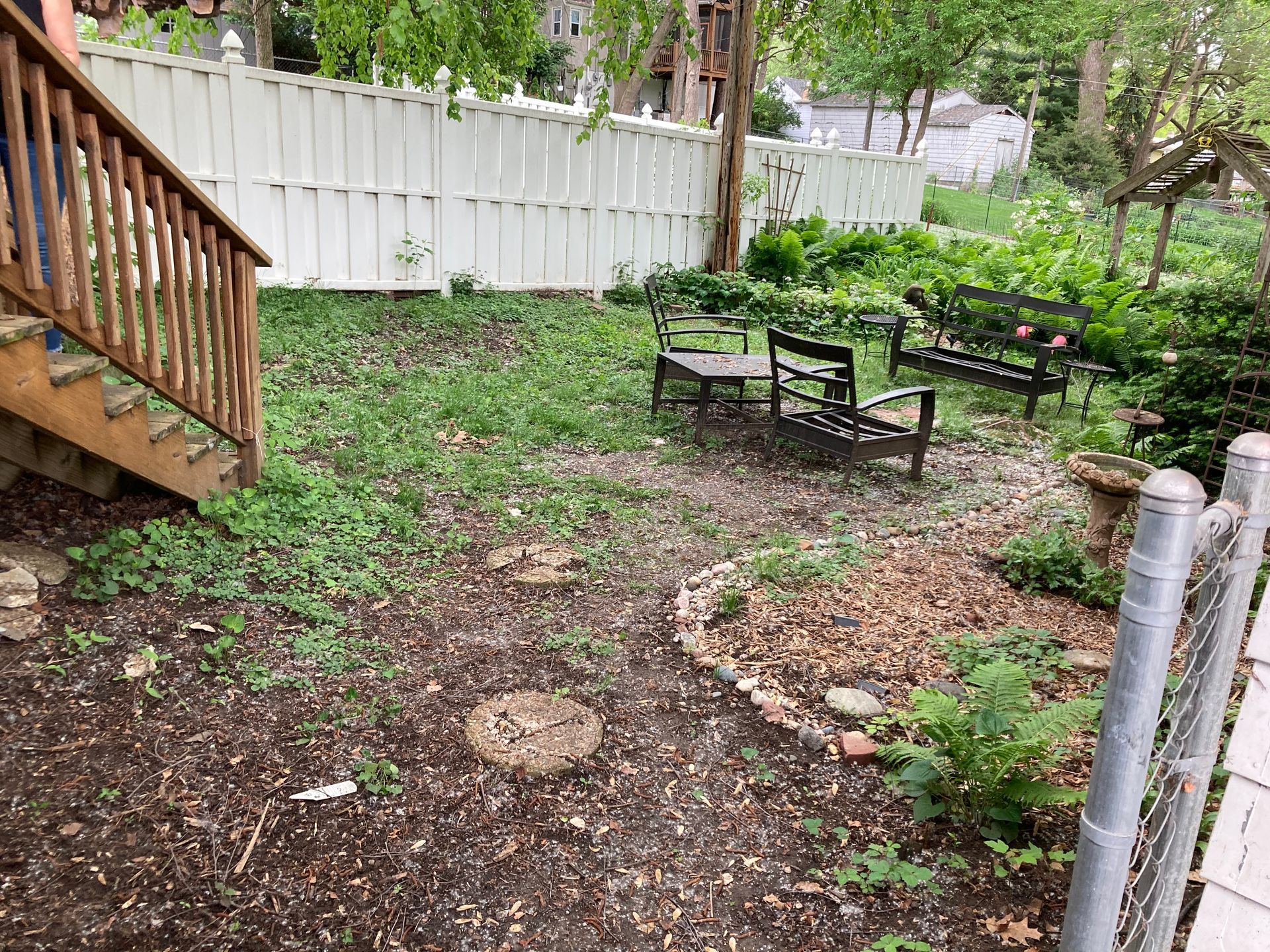 a backyard with a white fence, benches, and stairs