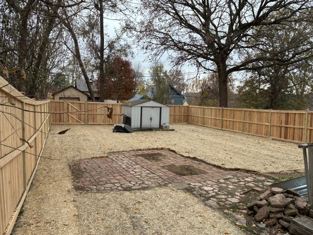 Backyard with an aged wood fence and patchy brown grass.