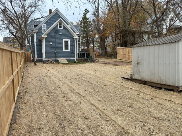 Backyard space with a rustic wooden fence and dry grass.