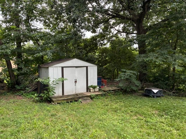 Backyard with a wooden house and green grass.