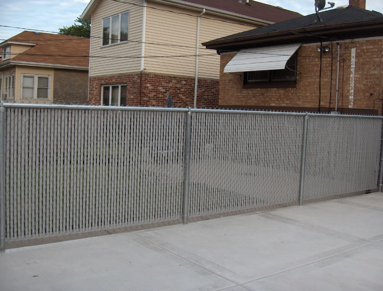 Gray metal fence with vertical lines in front of brick houses.