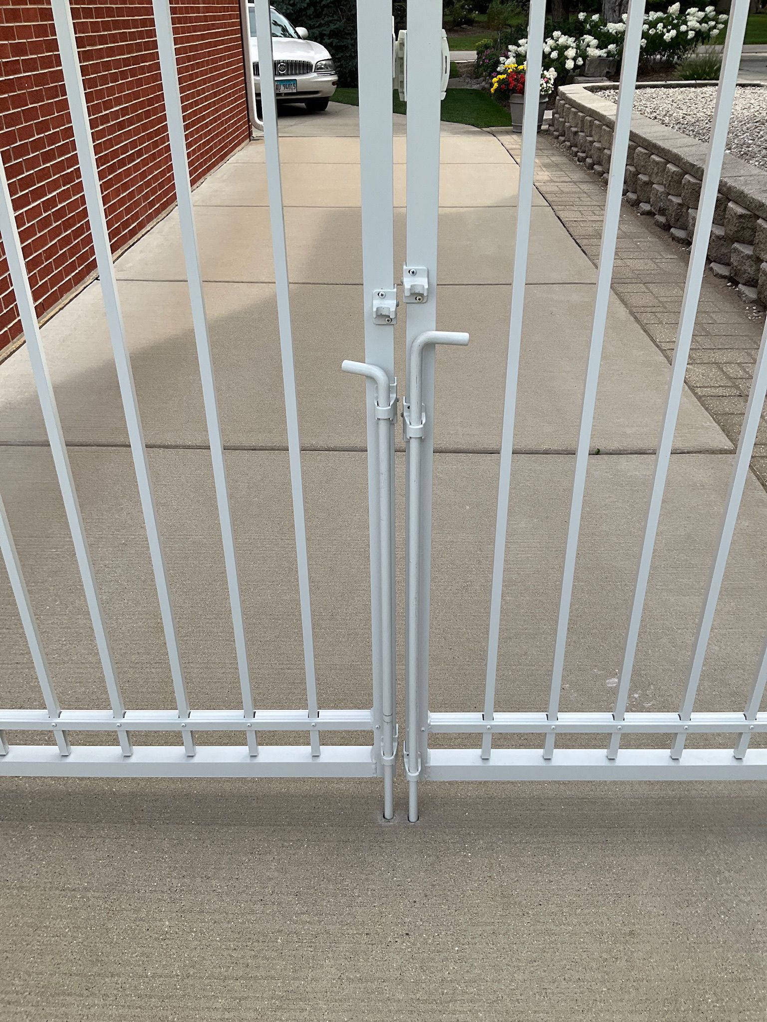 White metal gate closed on concrete driveway.