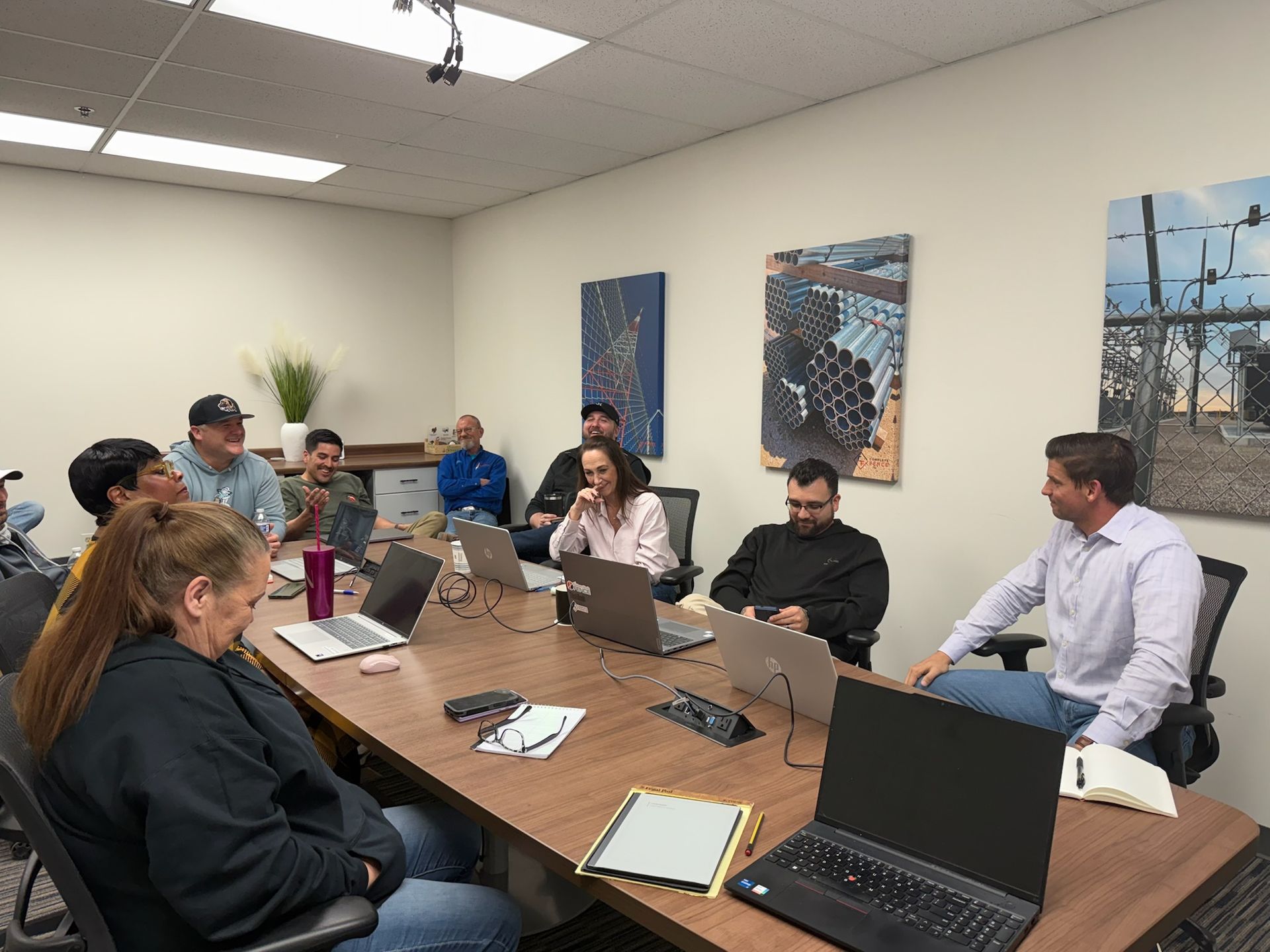 People seated around a conference table in an office, laptops open, engaged in a meeting.