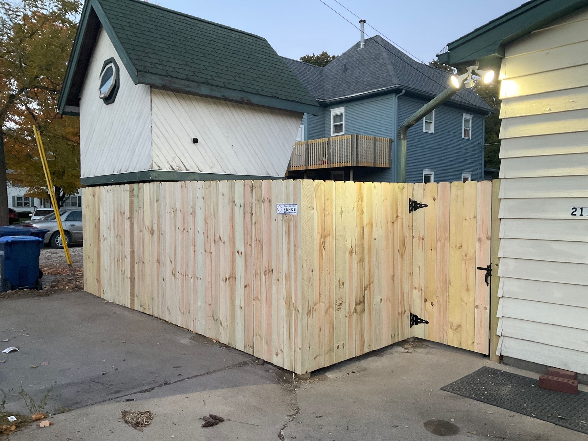 Wooden fence with gate, exterior of buildings in background.