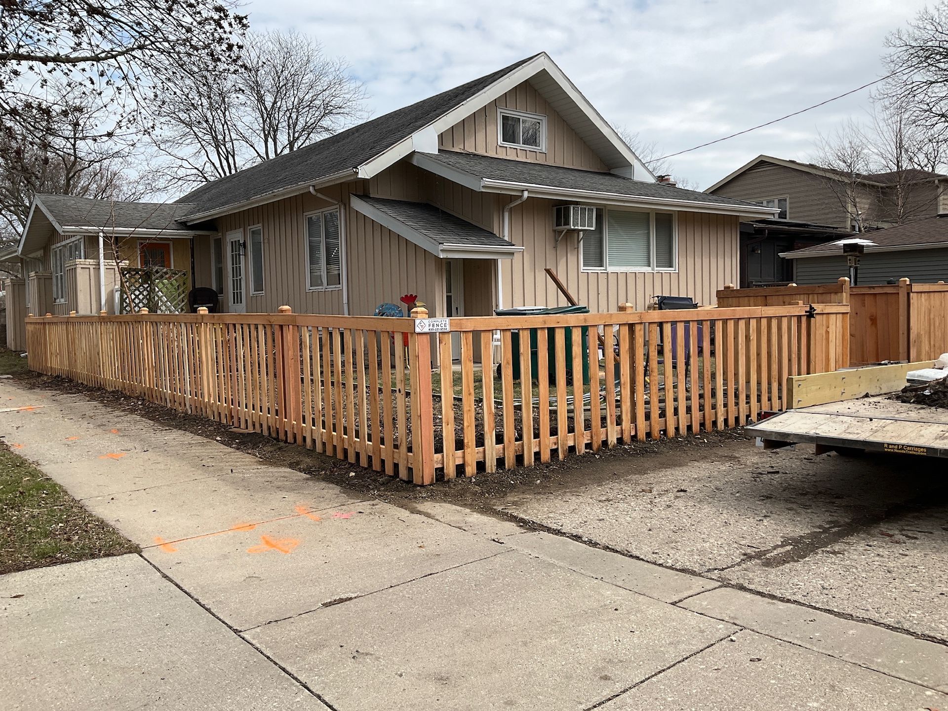 Tan house with new wooden fence along the sidewalk.