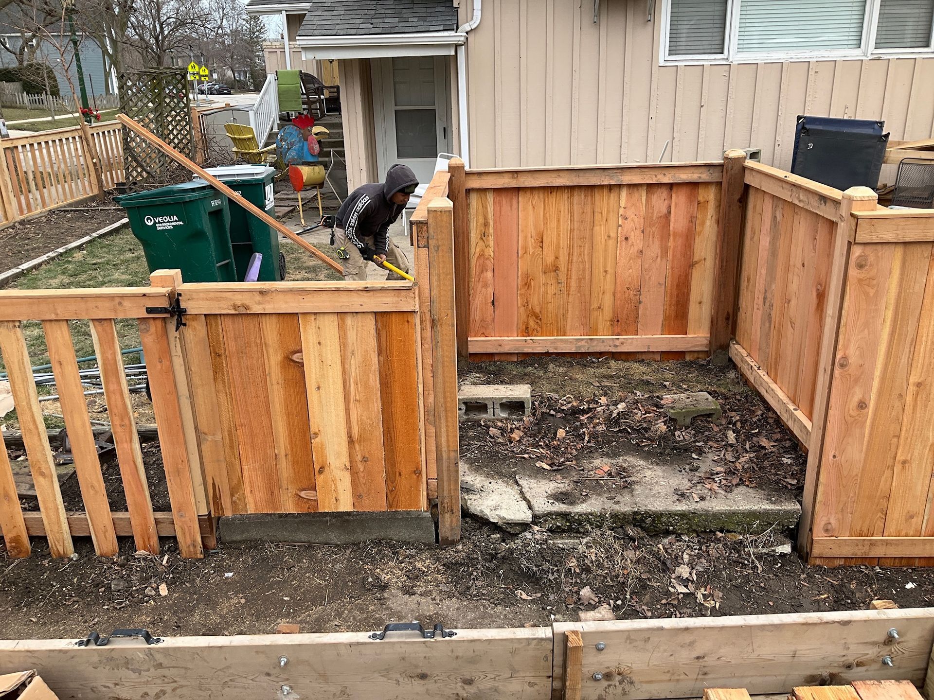 New wooden fence section with a gate being built around a trash enclosure.